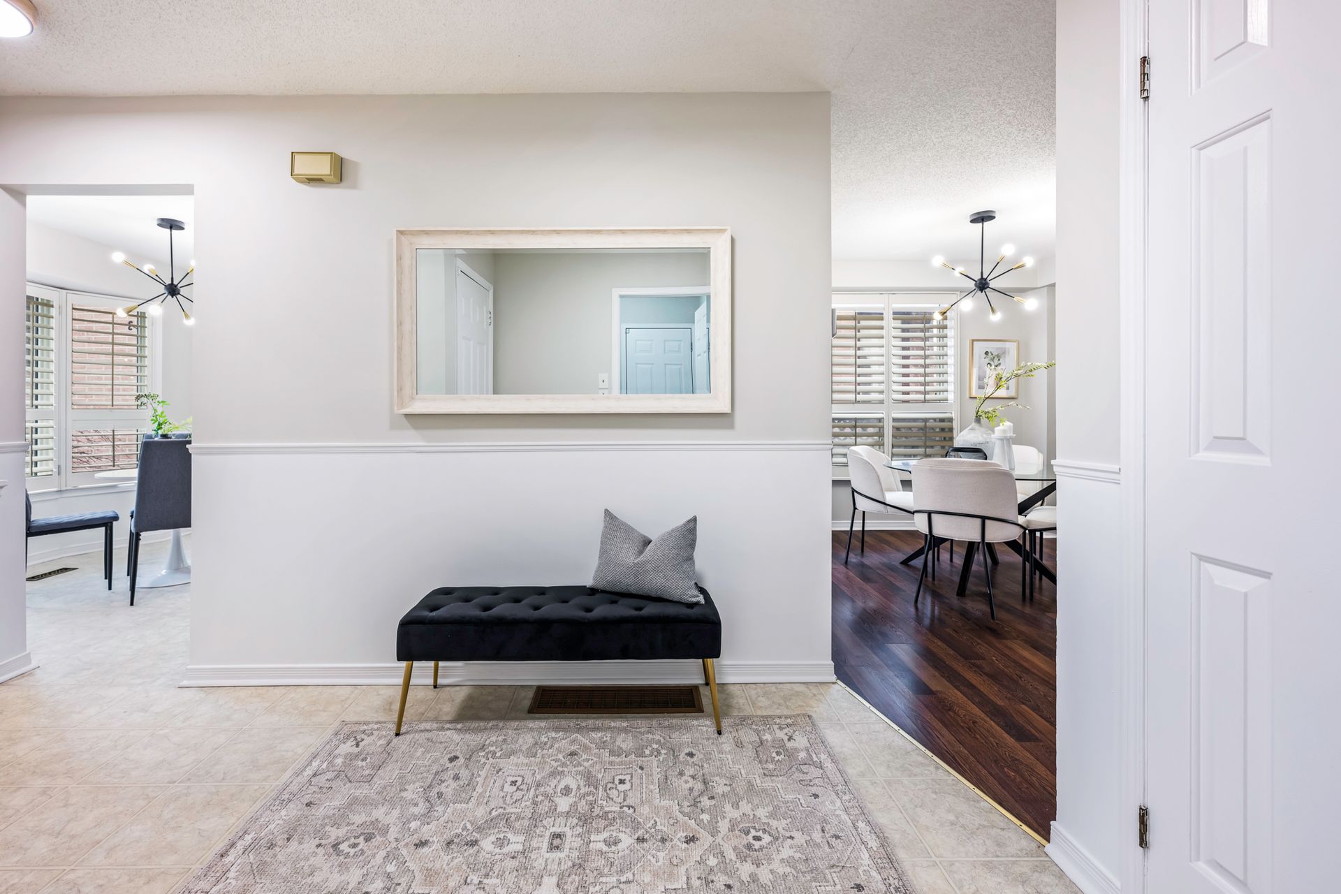 A hallway with a bench and a large mirror on the wall.