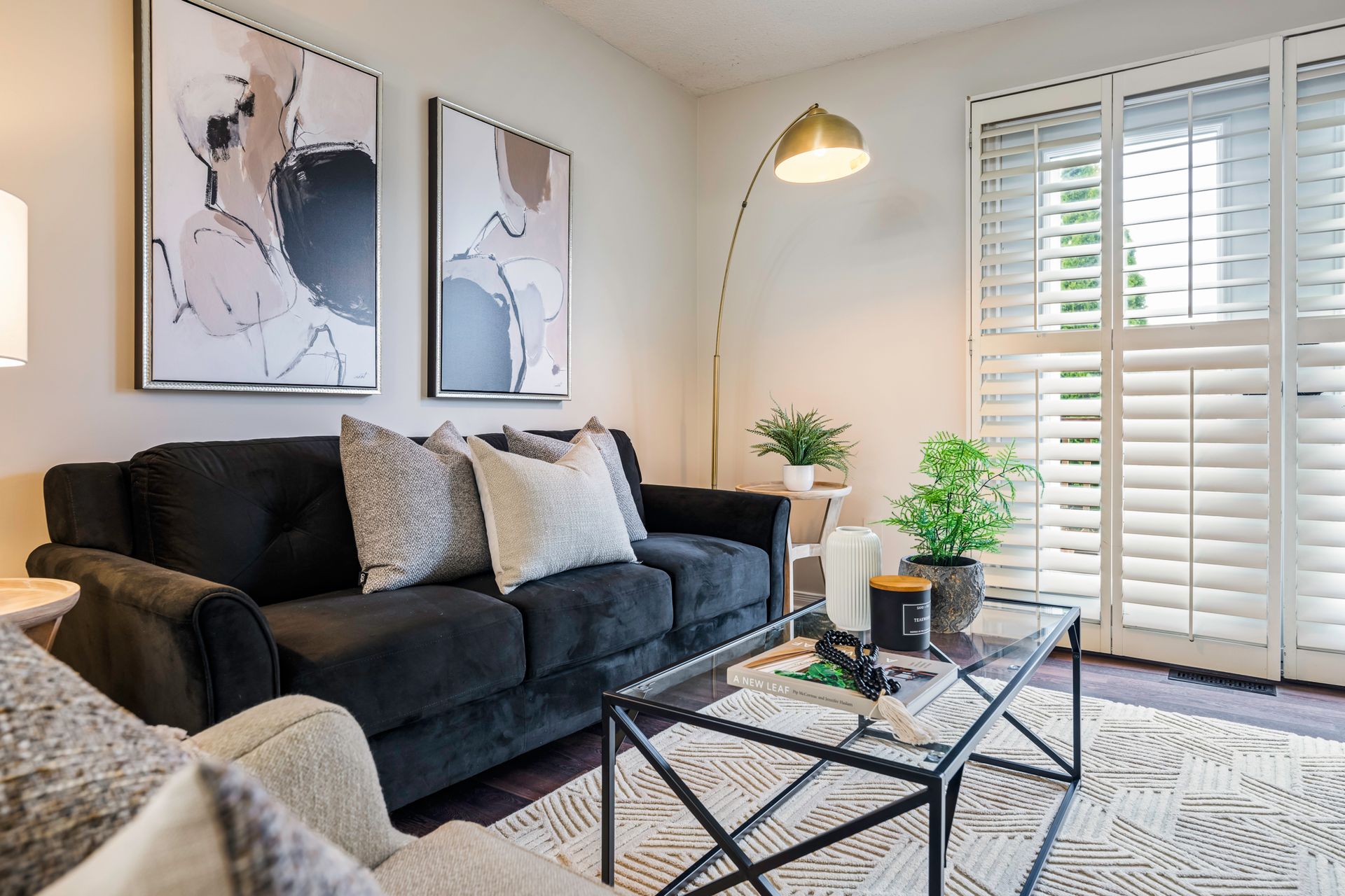 A living room with a black couch and a glass coffee table.