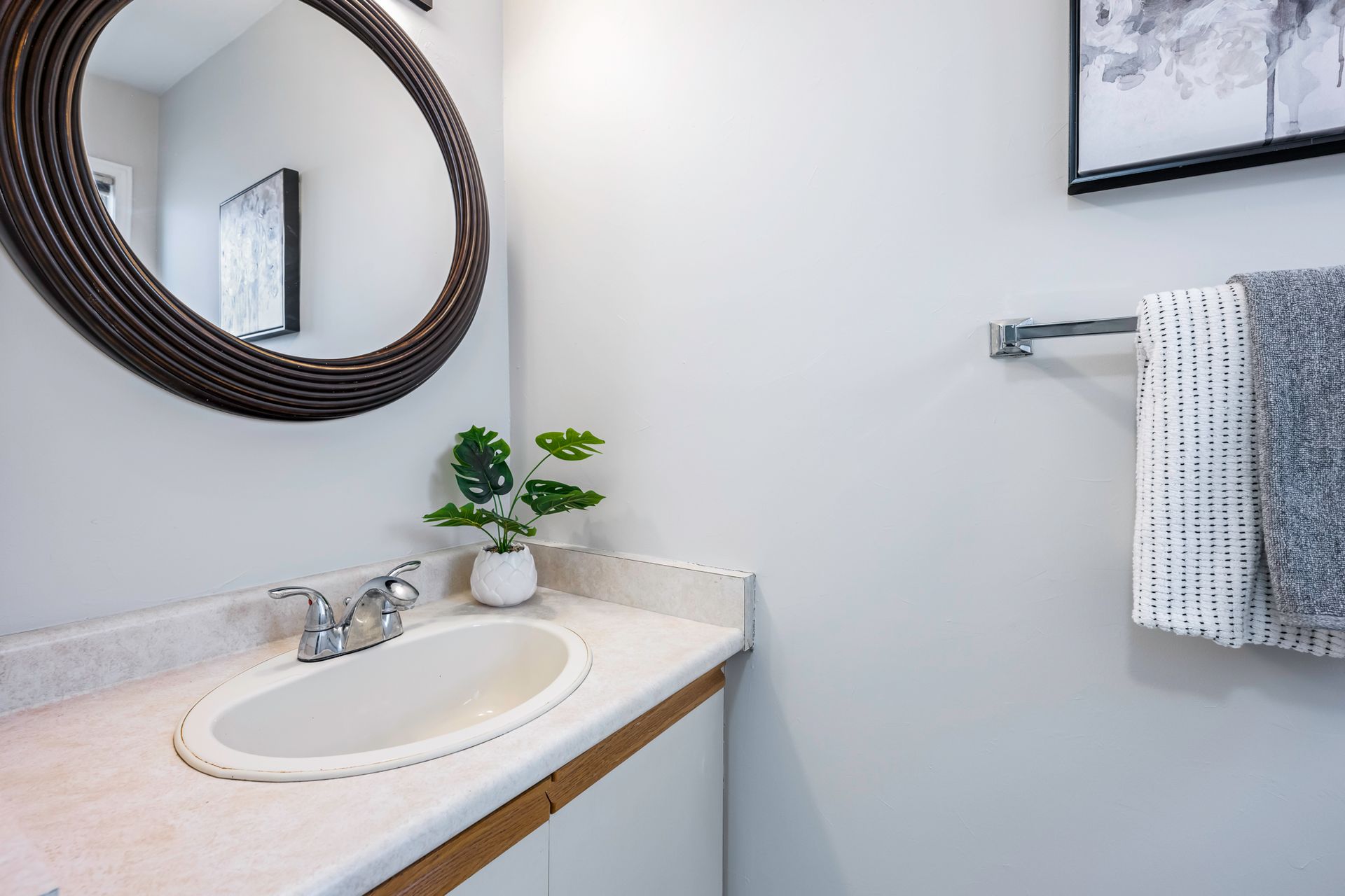 A bathroom with a sink , mirror and towel rack.