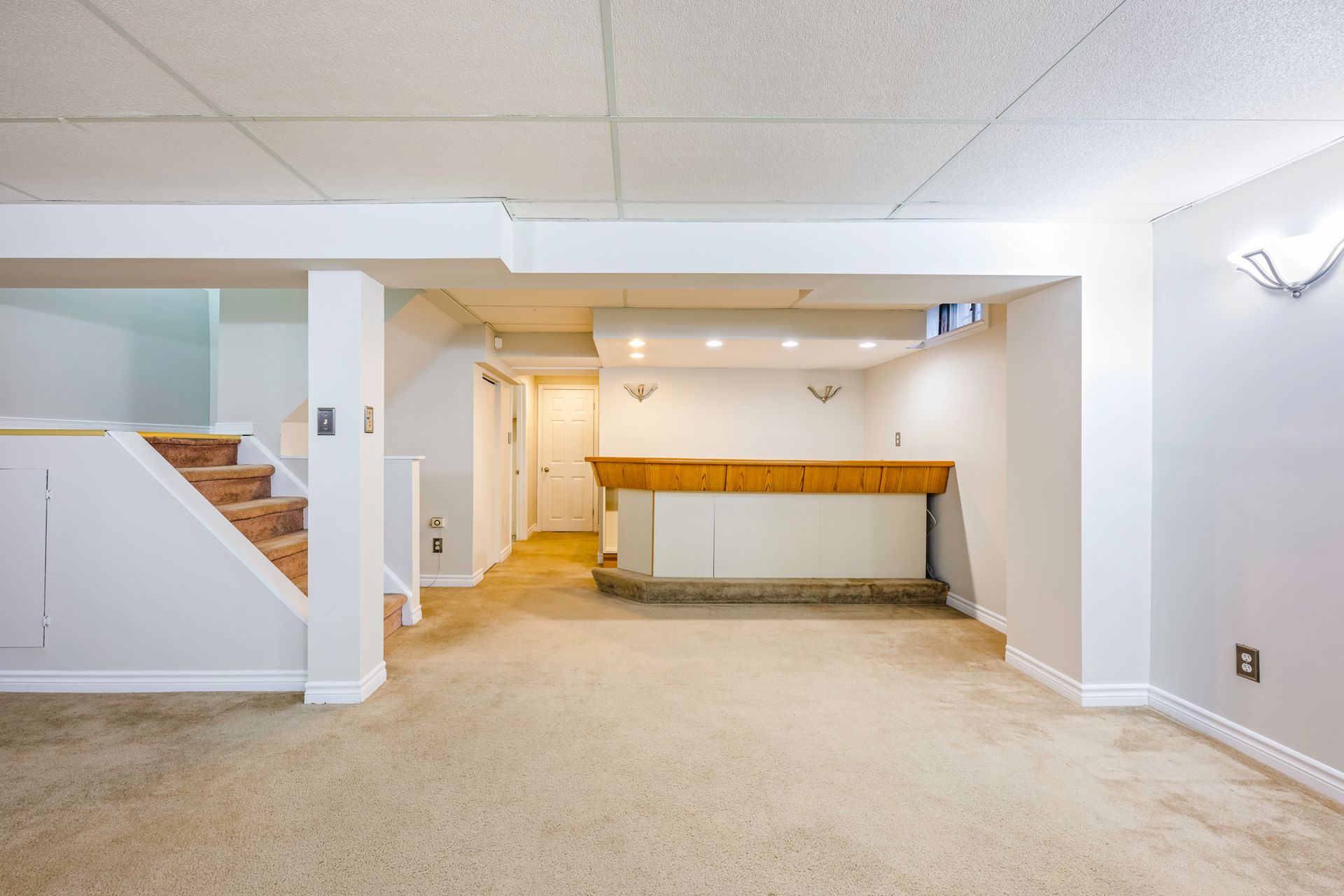 An empty basement with a bar and stairs.