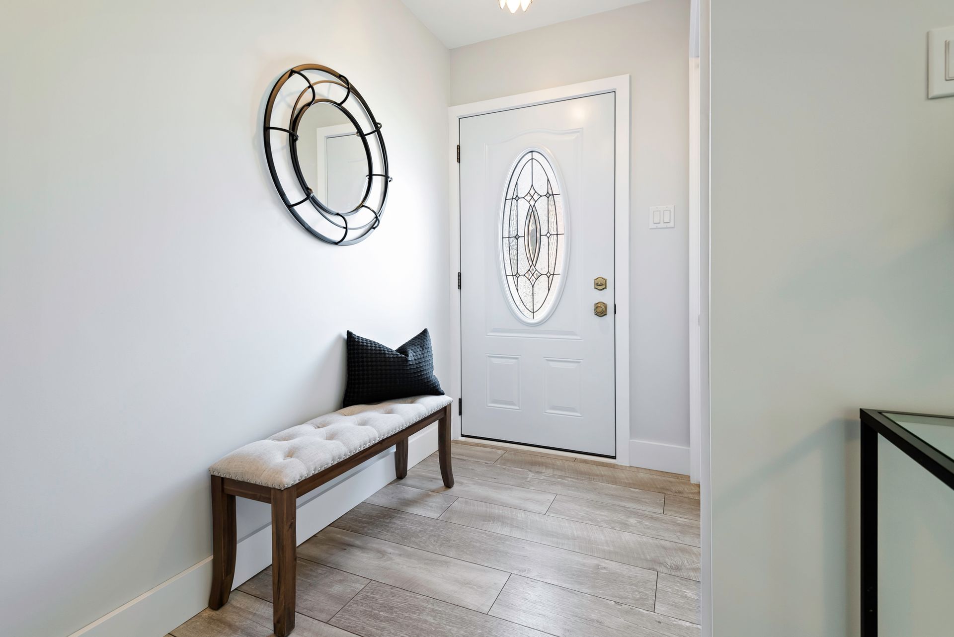 A hallway with a bench and a mirror above the door.