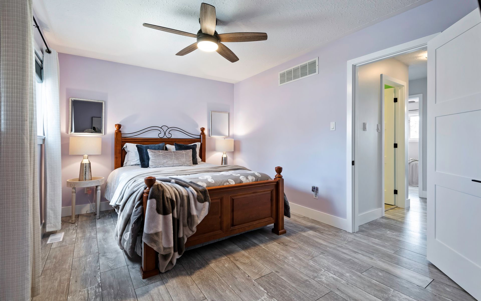 A bedroom with a large bed and a ceiling fan.