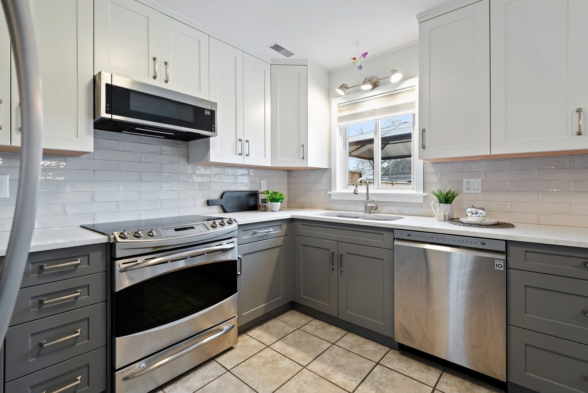 A kitchen with stainless steel appliances and gray cabinets.