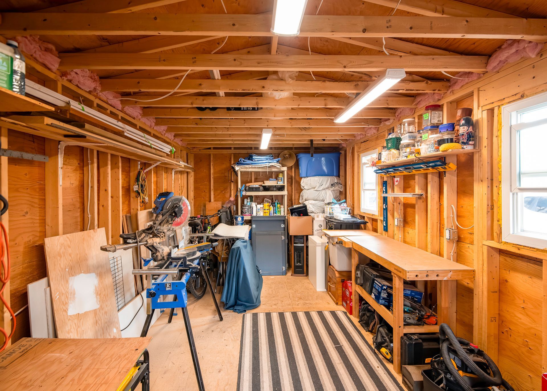 A wooden garage filled with tools and a striped rug.
