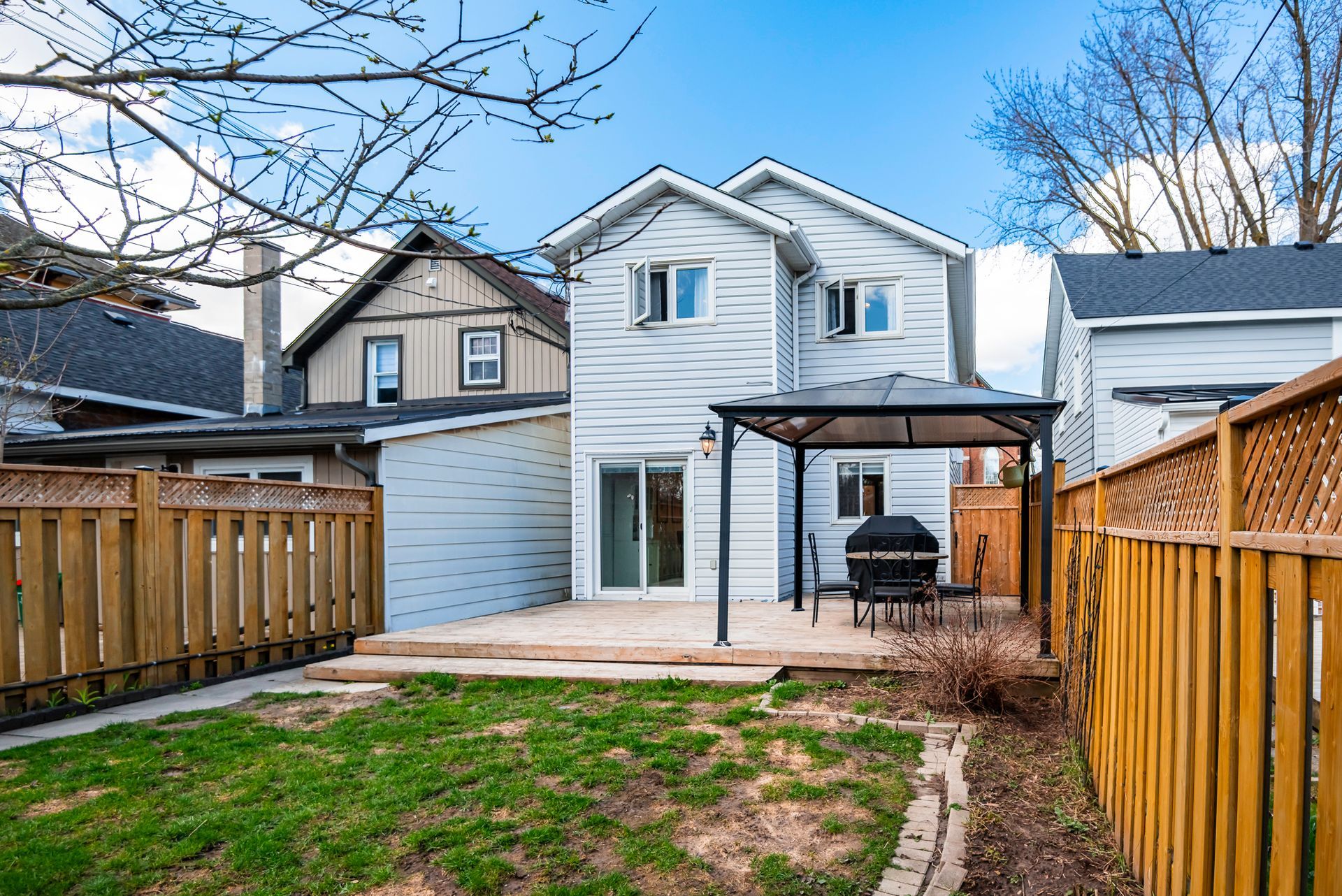 The backyard of a house with a patio and a wooden fence.