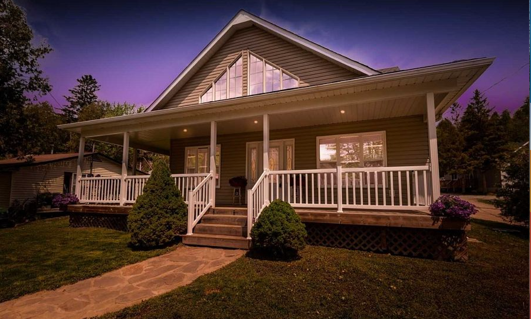 A house with a porch and stairs is lit up at night.