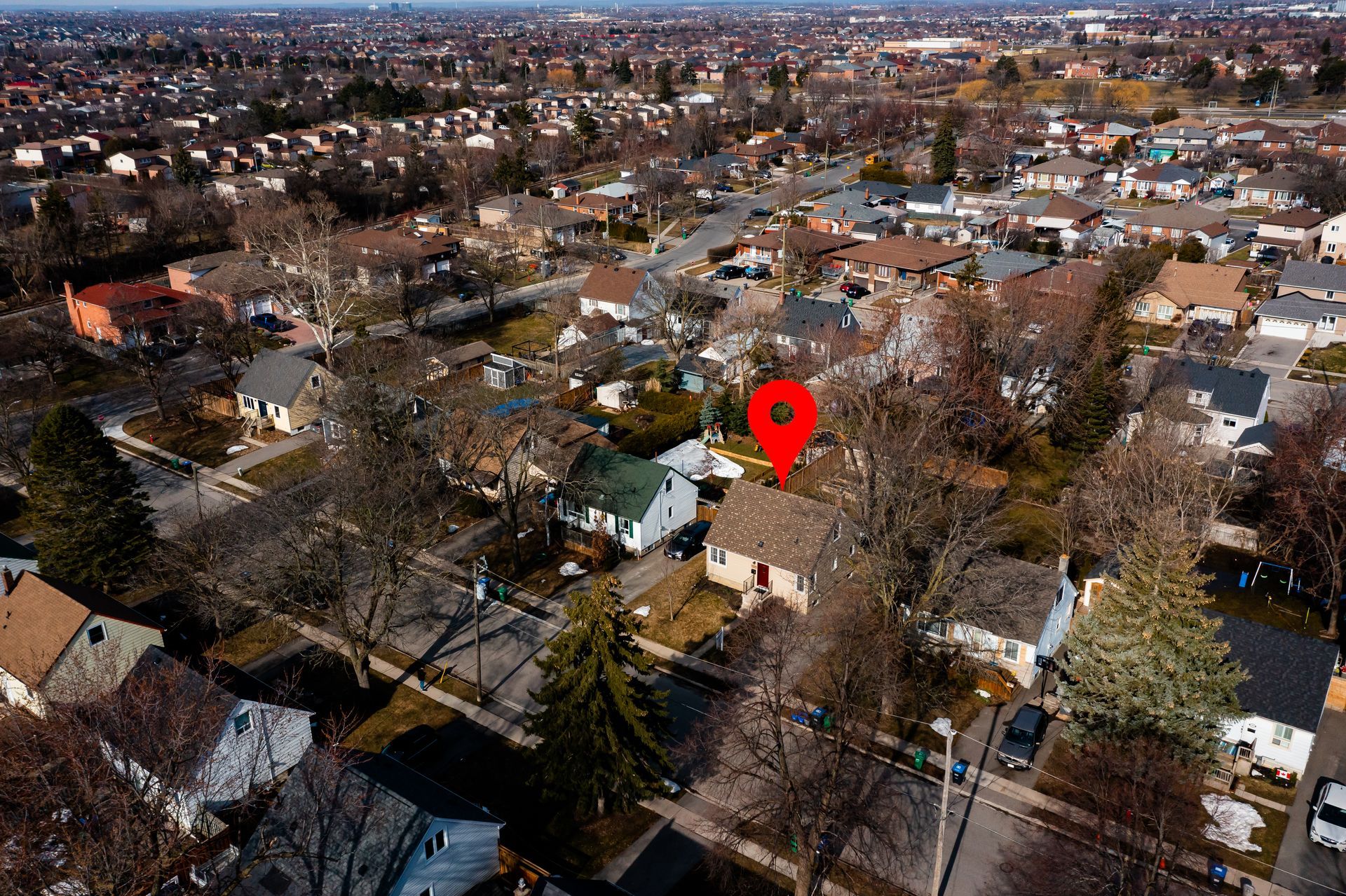 An aerial view of a residential area with a red pin pointing the location of a house.
