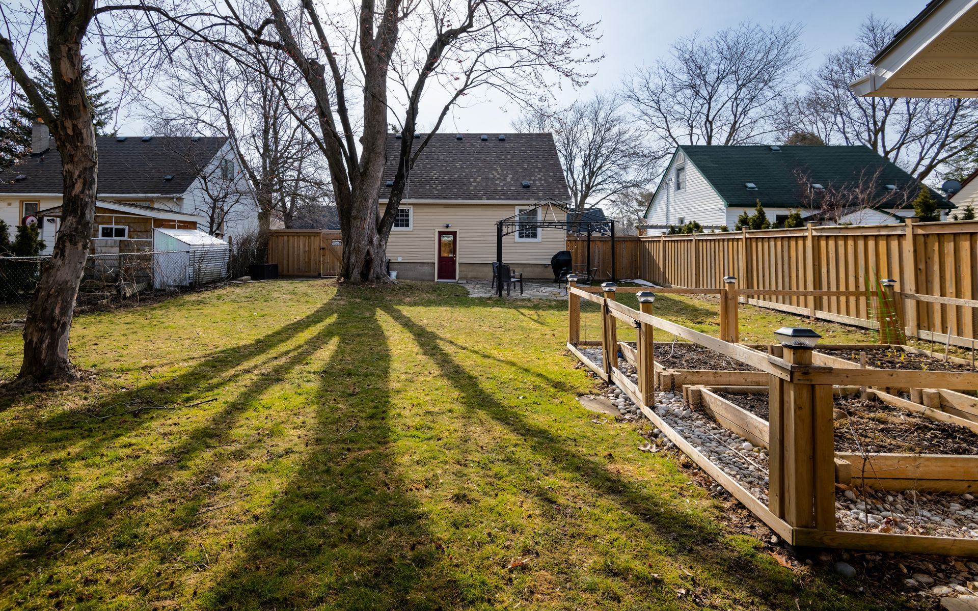 A backyard with a wooden fence and a basketball hoop.