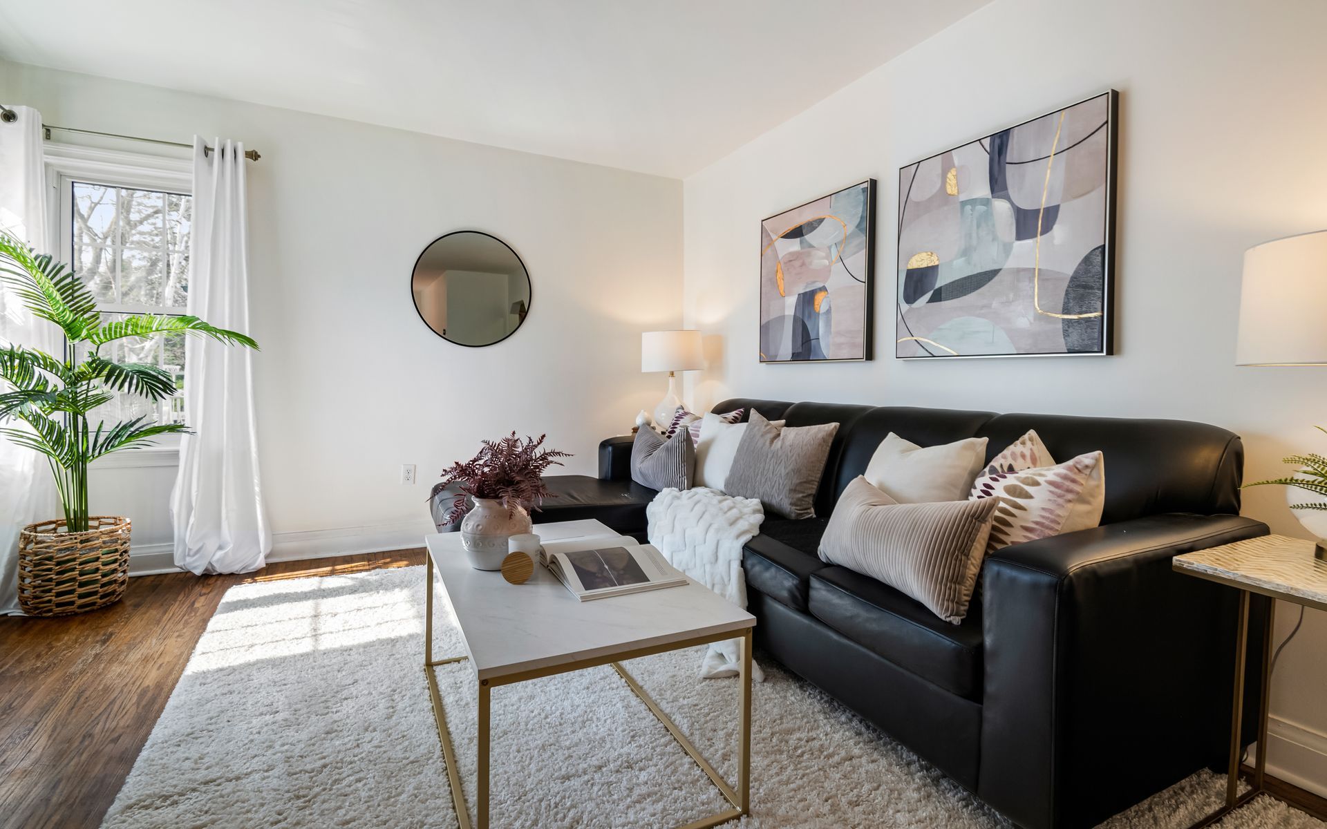 A living room with a black couch and a white coffee table.