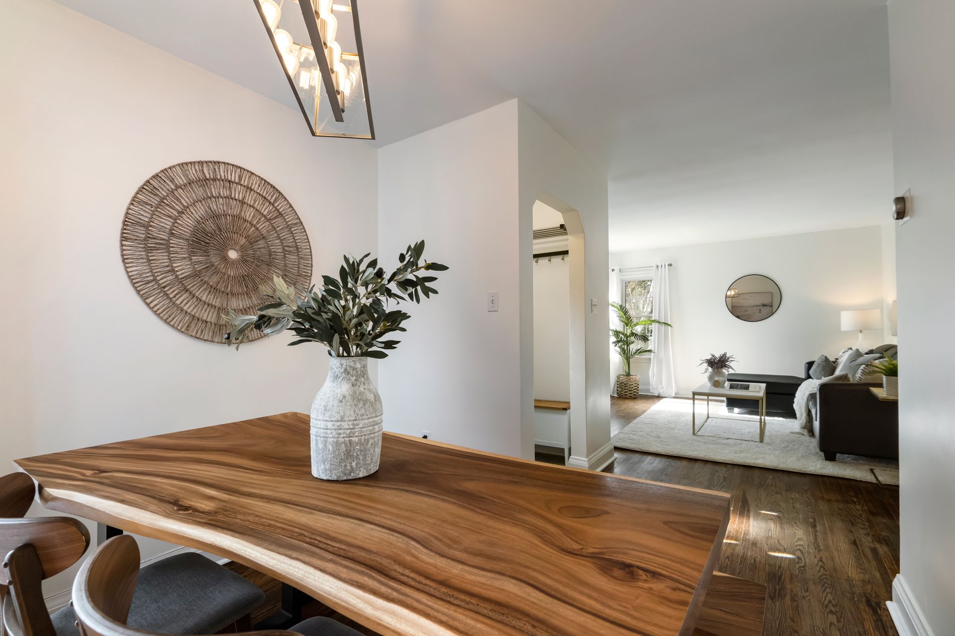 A wooden table with a vase of flowers on it in a dining room.