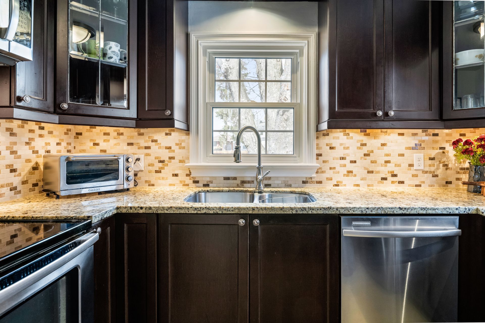 A kitchen with stainless steel appliances , a sink , and a window.