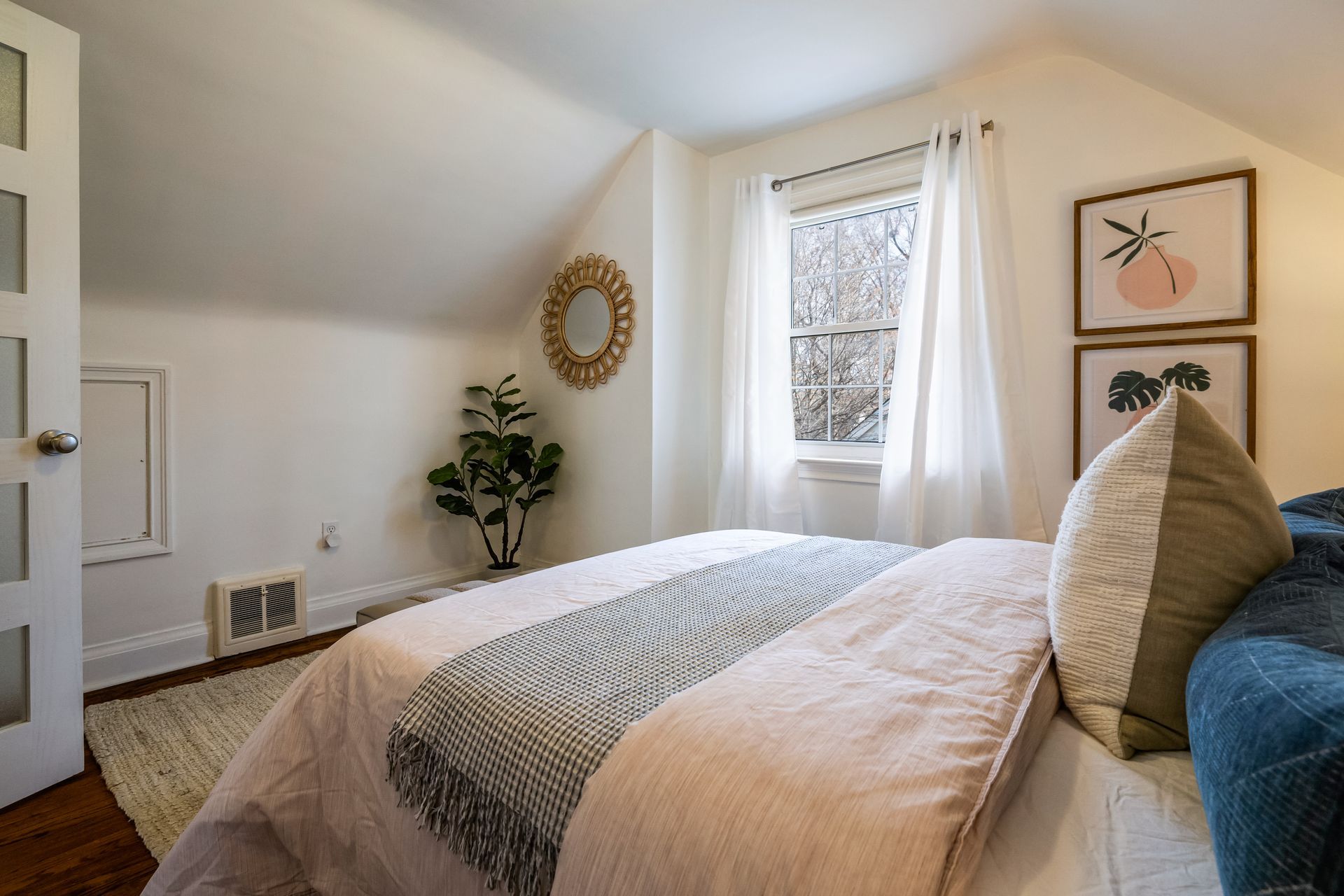 A bedroom with a bed , a window and a plant.