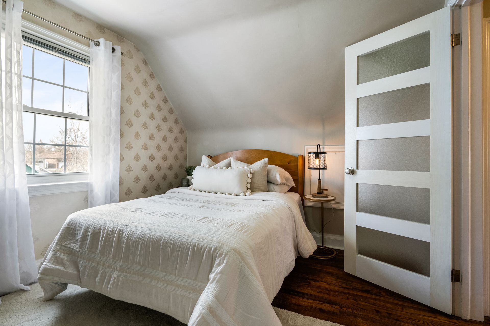 A bedroom with a bed , a window and a door.