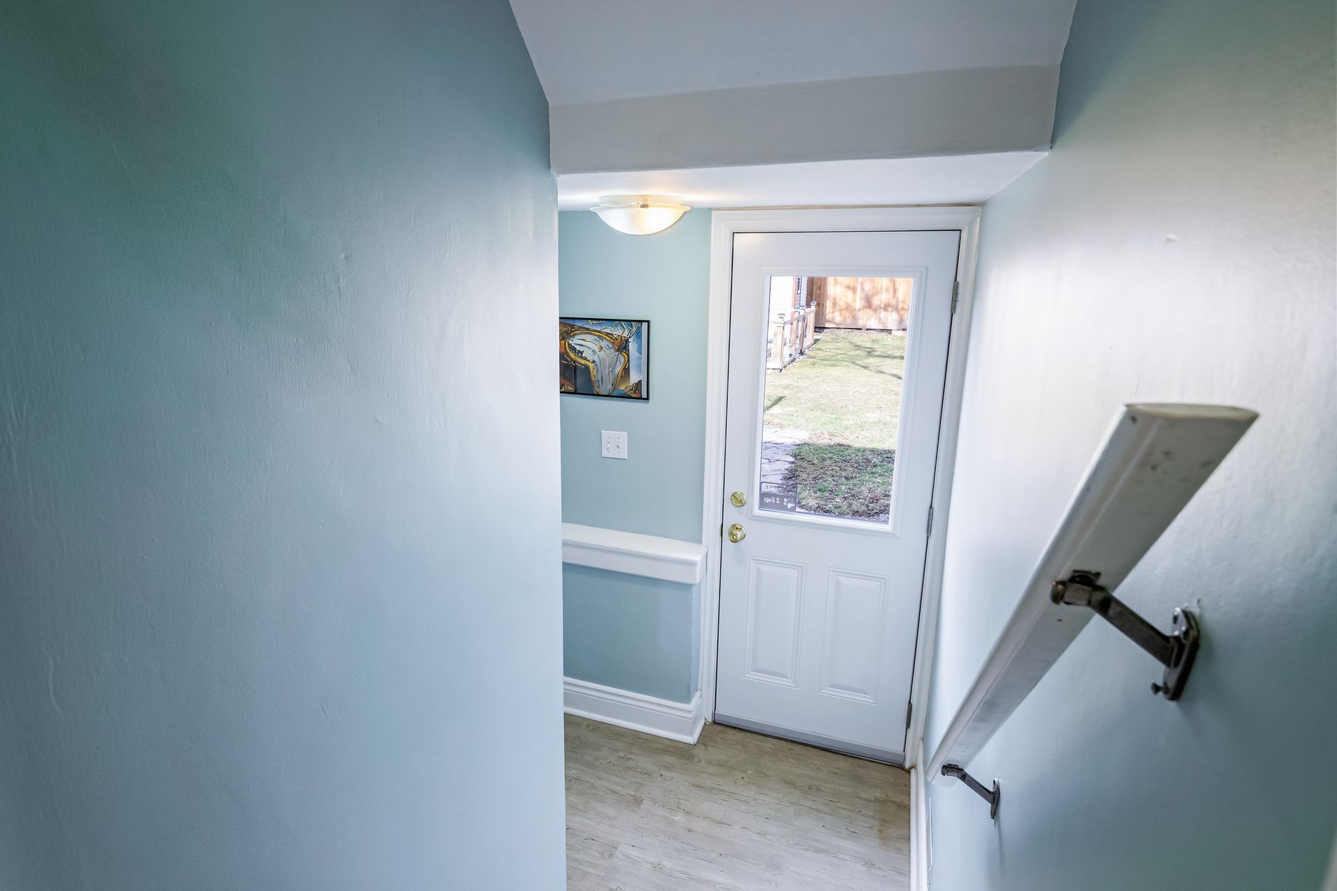 A hallway with a white door and stairs leading up to it.