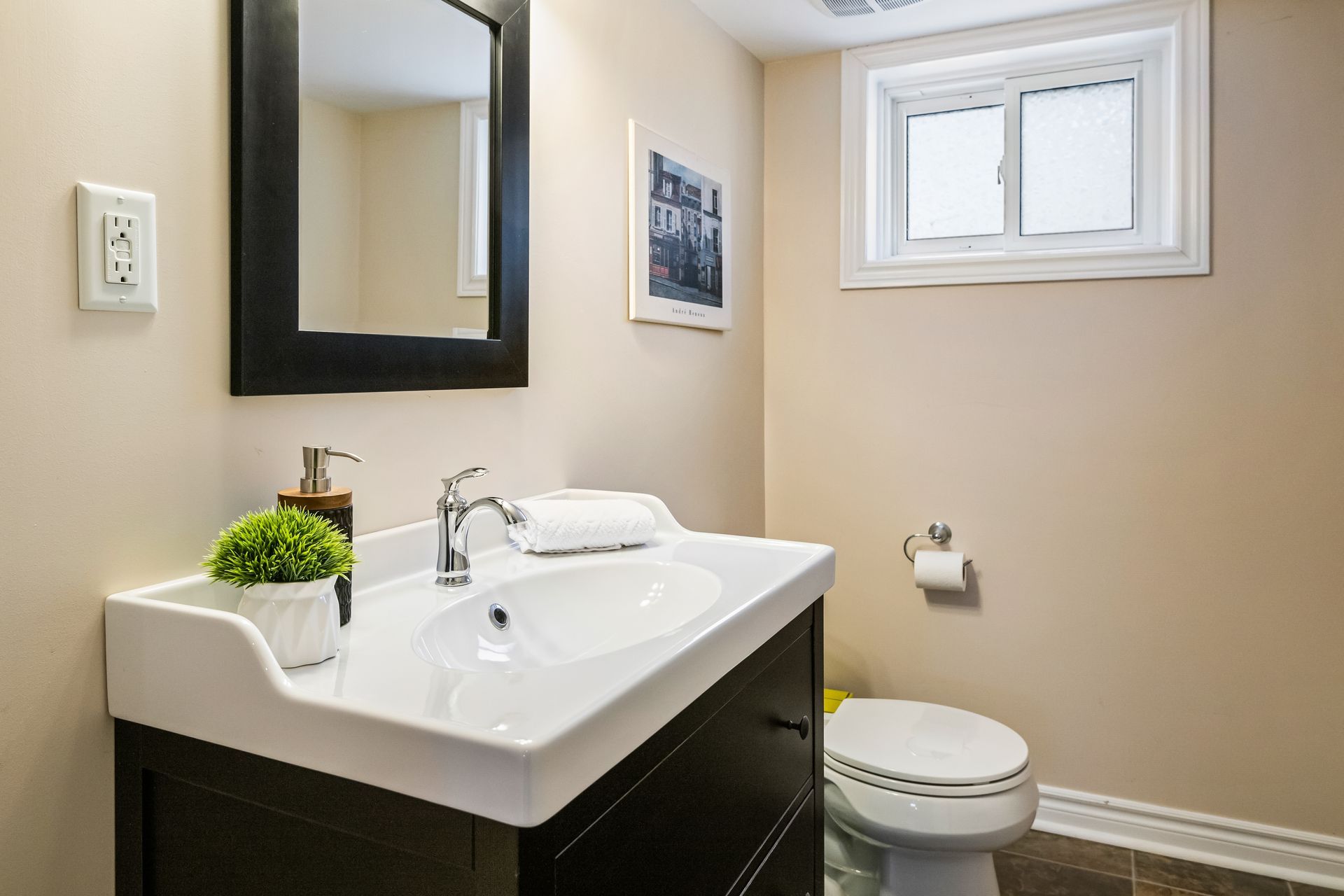 A bathroom with a sink , toilet , mirror and window.
