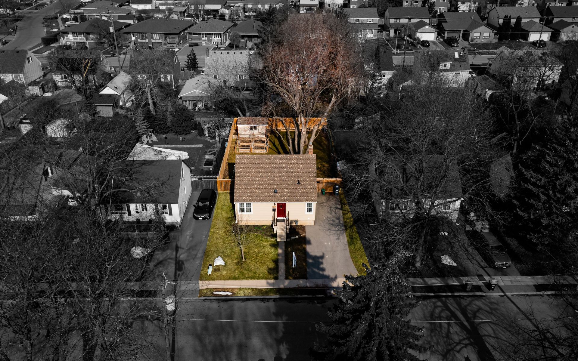 An aerial view of a house in a residential area surrounded by trees.