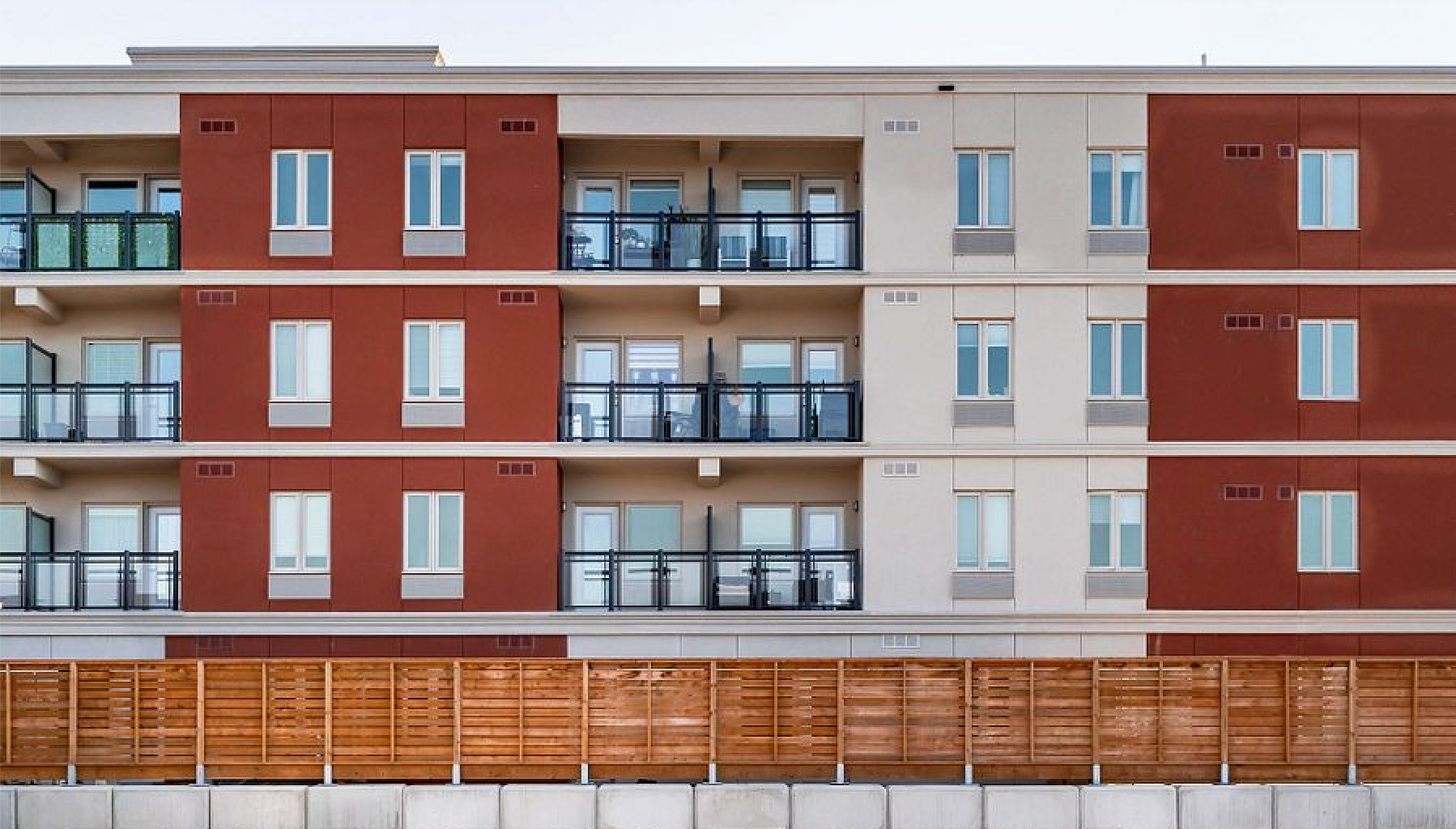 A large apartment building with a wooden fence in front of it.