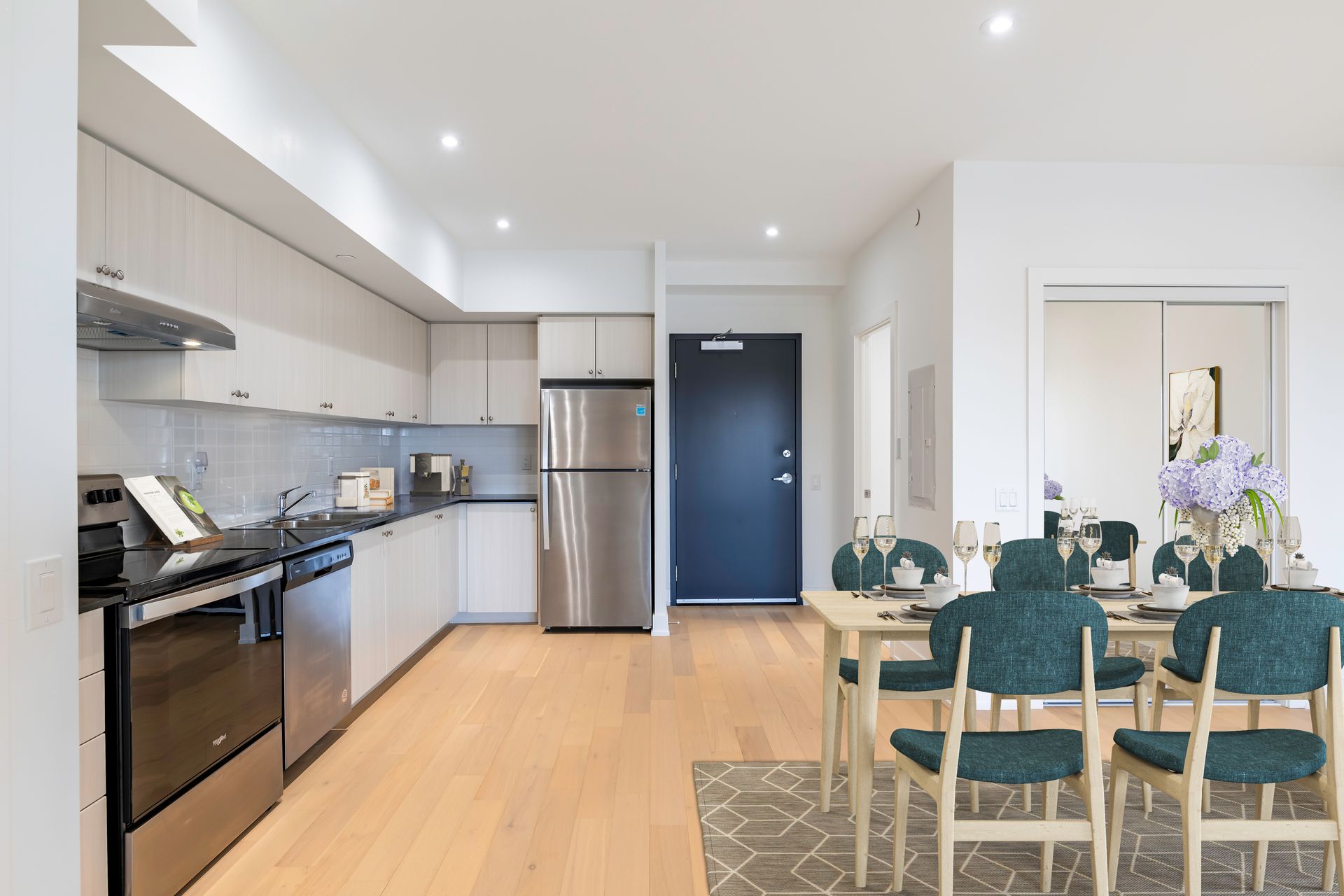 A kitchen with stainless steel appliances and a dining room with a table and chairs.