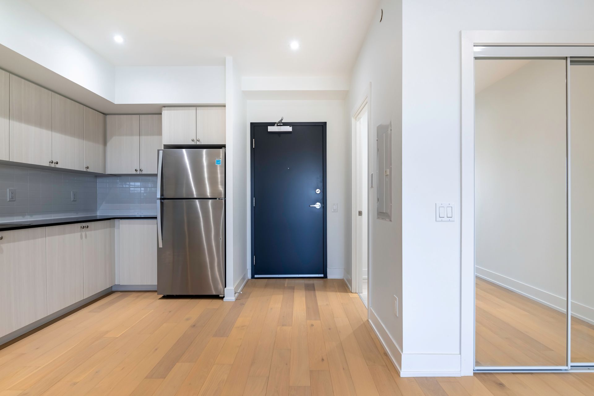 A kitchen with a stainless steel refrigerator and a black door