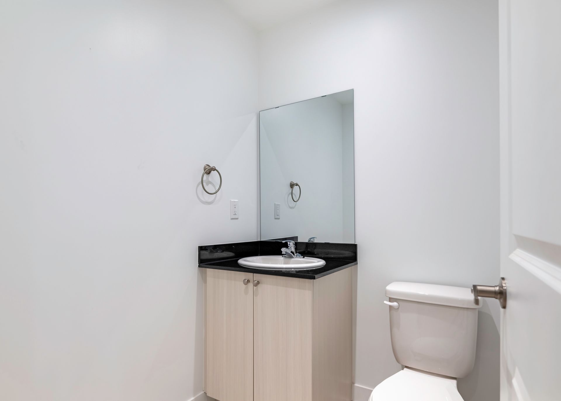 A bathroom with a toilet , sink and mirror.