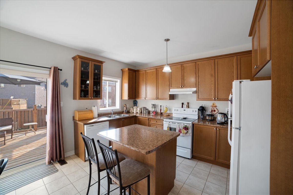 A kitchen with wooden cabinets , granite counter tops , a refrigerator and a stove.
