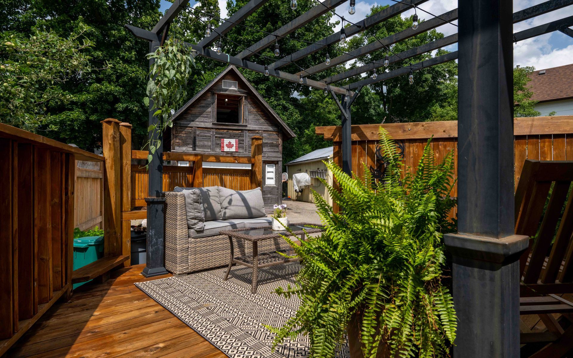 A patio with a couch , chairs , and a pergola.