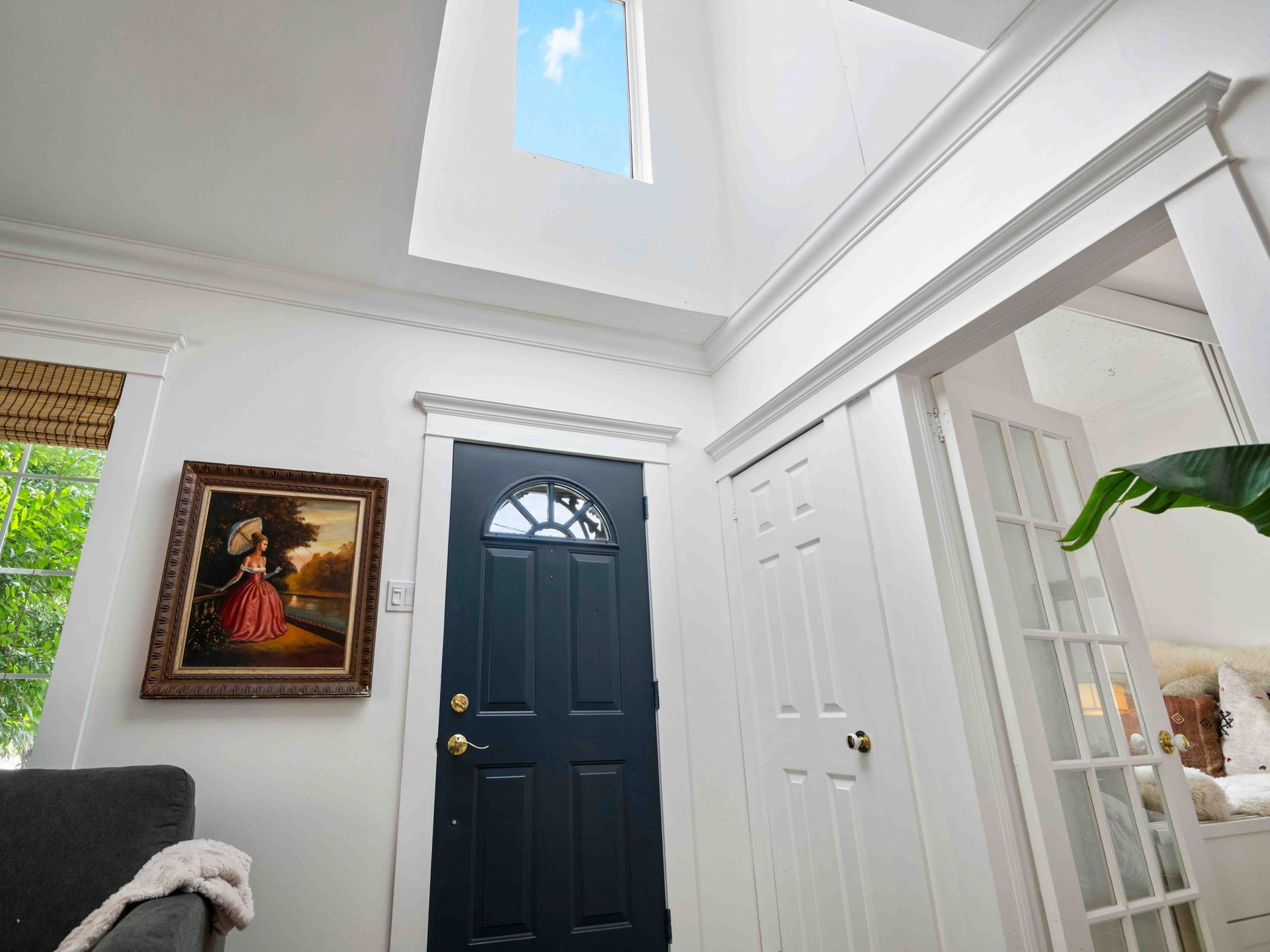 A living room with a black door and a skylight above it.