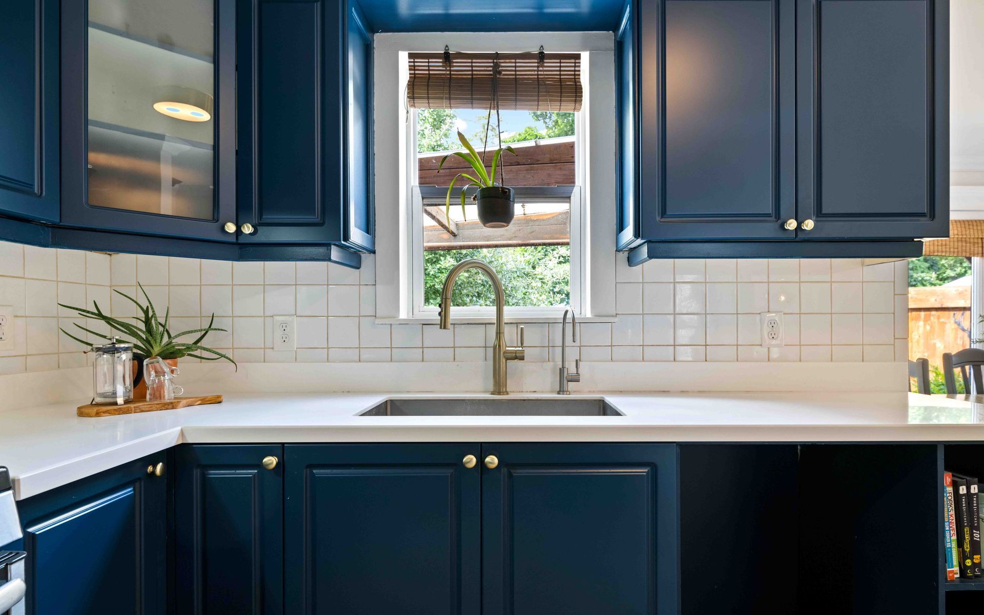 A kitchen with blue cabinets , a sink , and a window.
