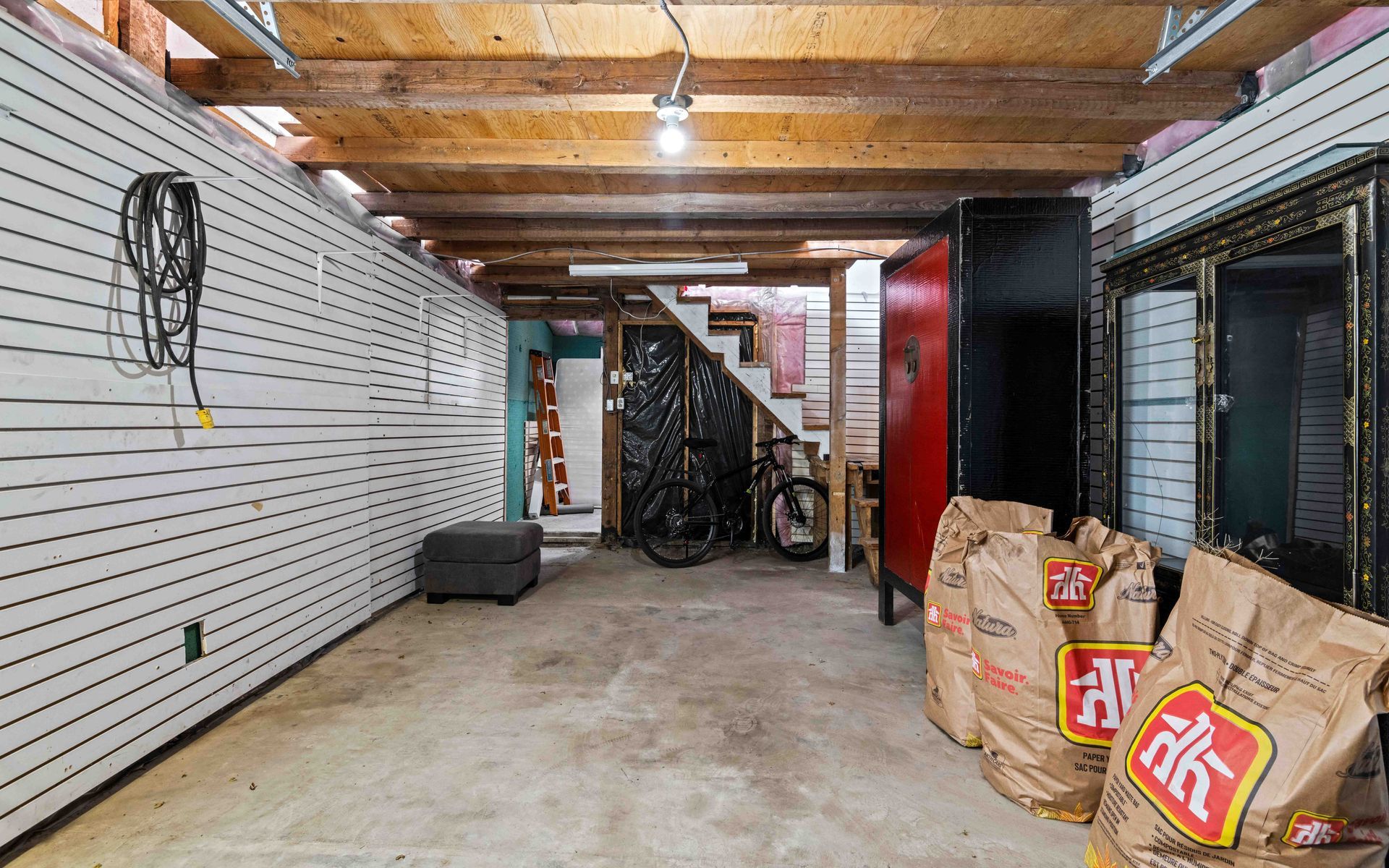 A large empty garage with bags of charcoal on the floor.