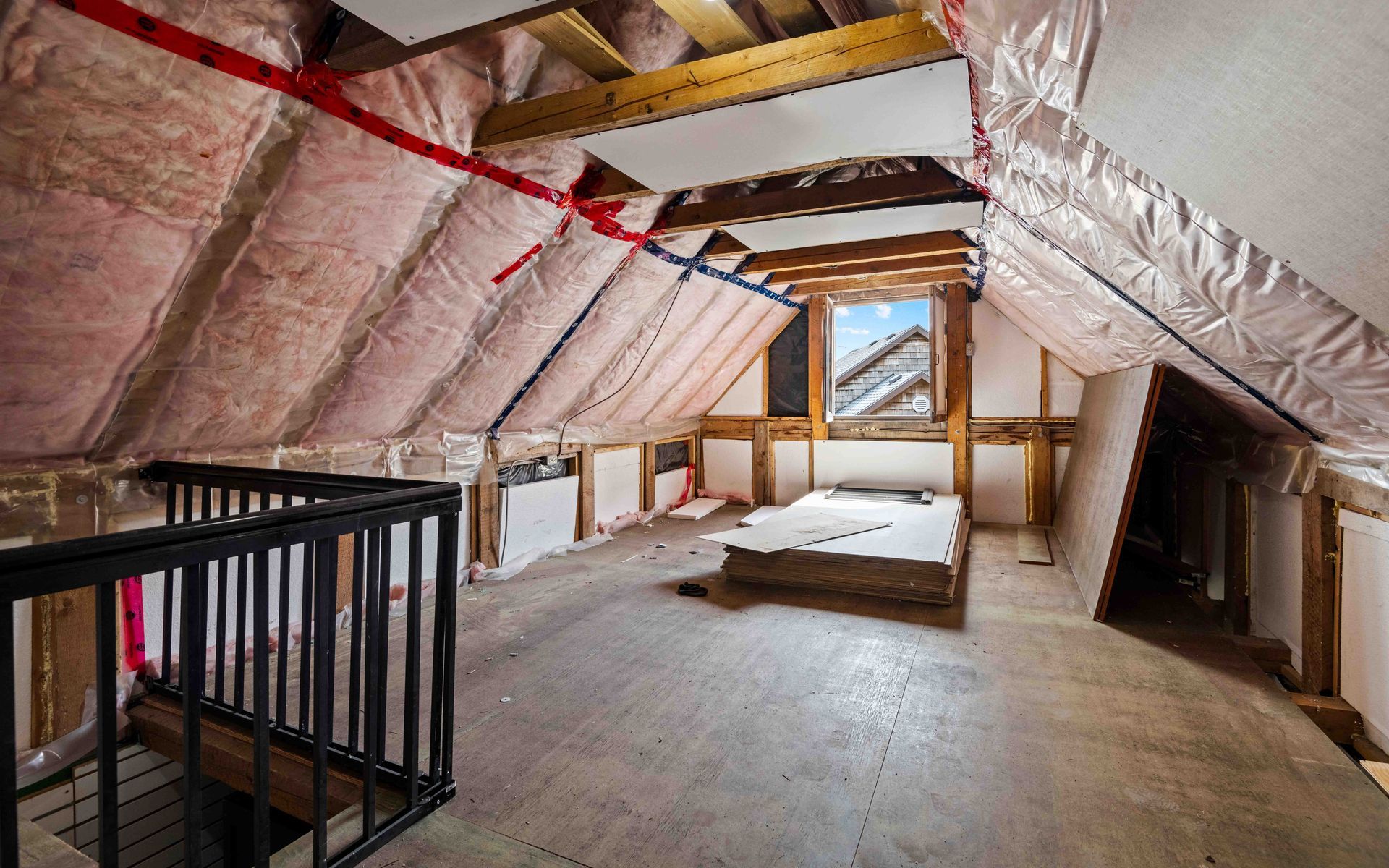 An empty attic with a staircase and a window.