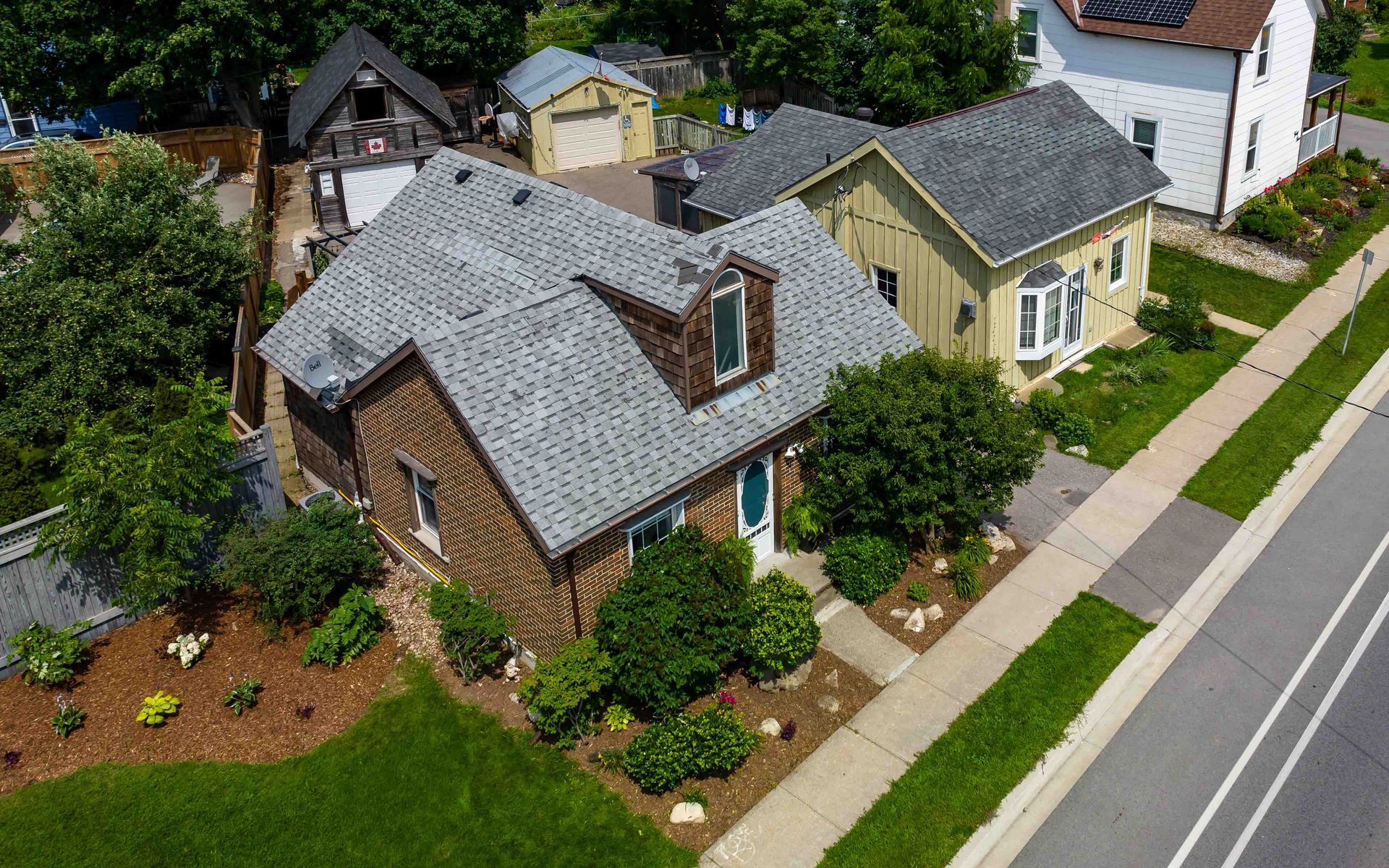 An aerial view of a residential neighborhood with a brick house and a white house.