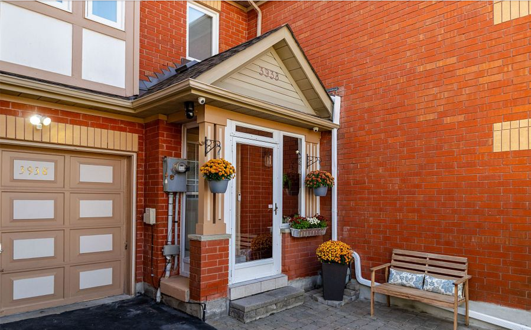 A brick house with a porch and a bench in front of it.