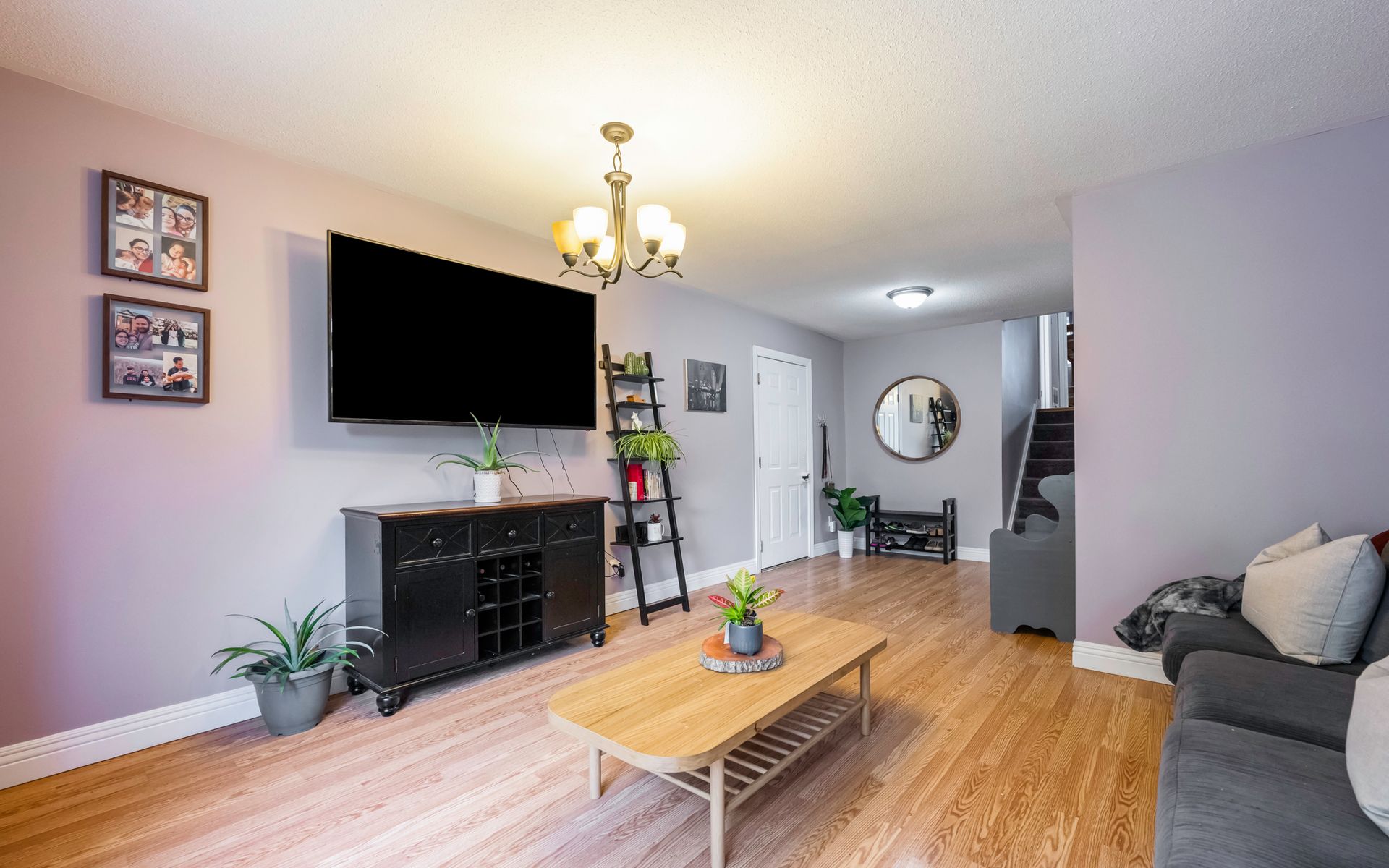 A living room with a couch , coffee table , television and stairs.