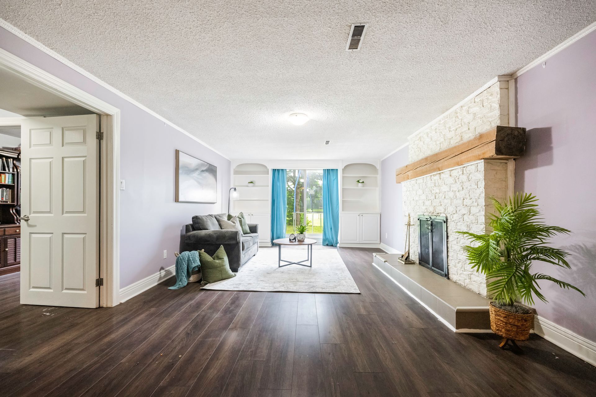 A living room with hardwood floors , a fireplace , and a couch.