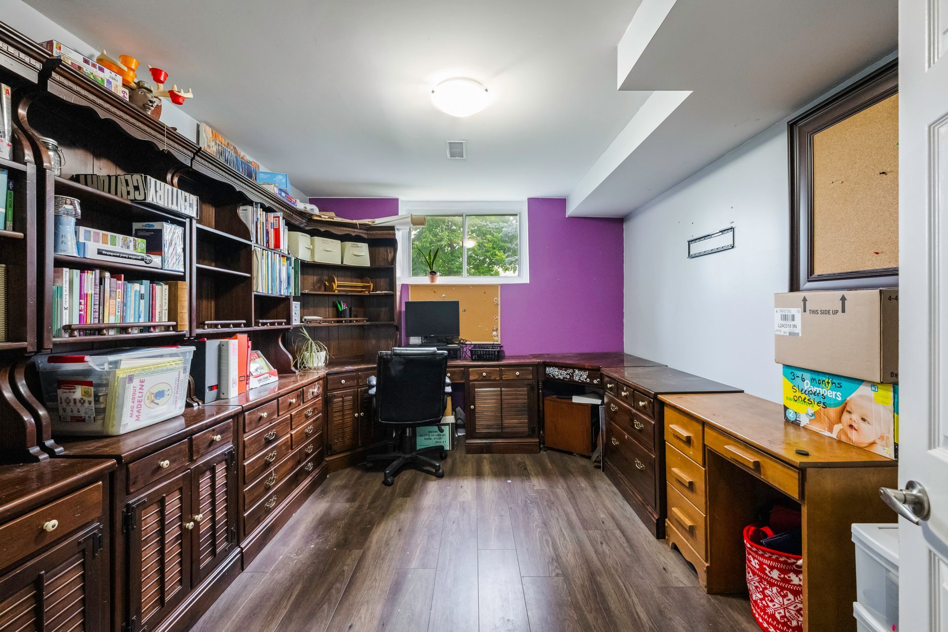 A room with a purple wall and lots of shelves and desks