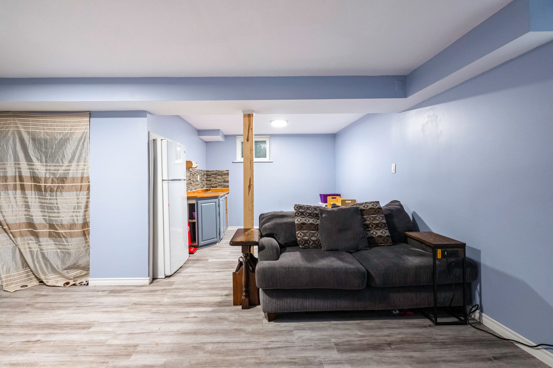 A living room in a basement with a couch and a table.