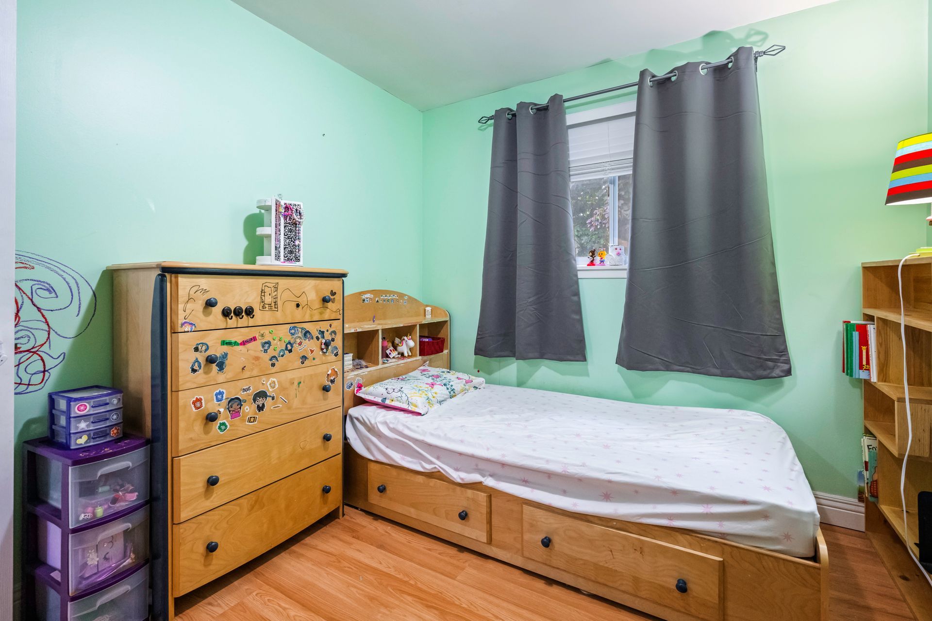 A bedroom with a bed , dresser , and window.