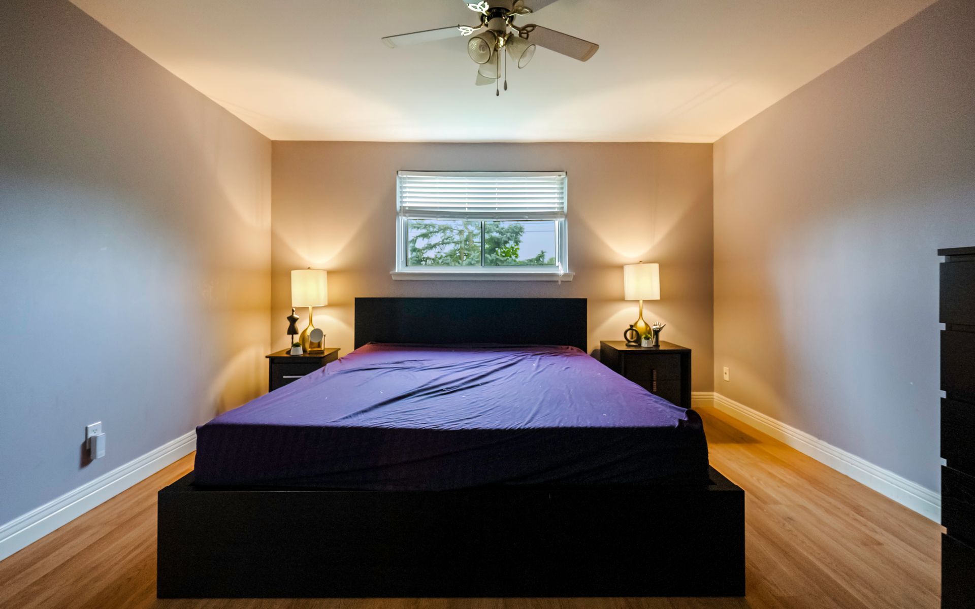A bedroom with a bed , two nightstands , a ceiling fan and a window.