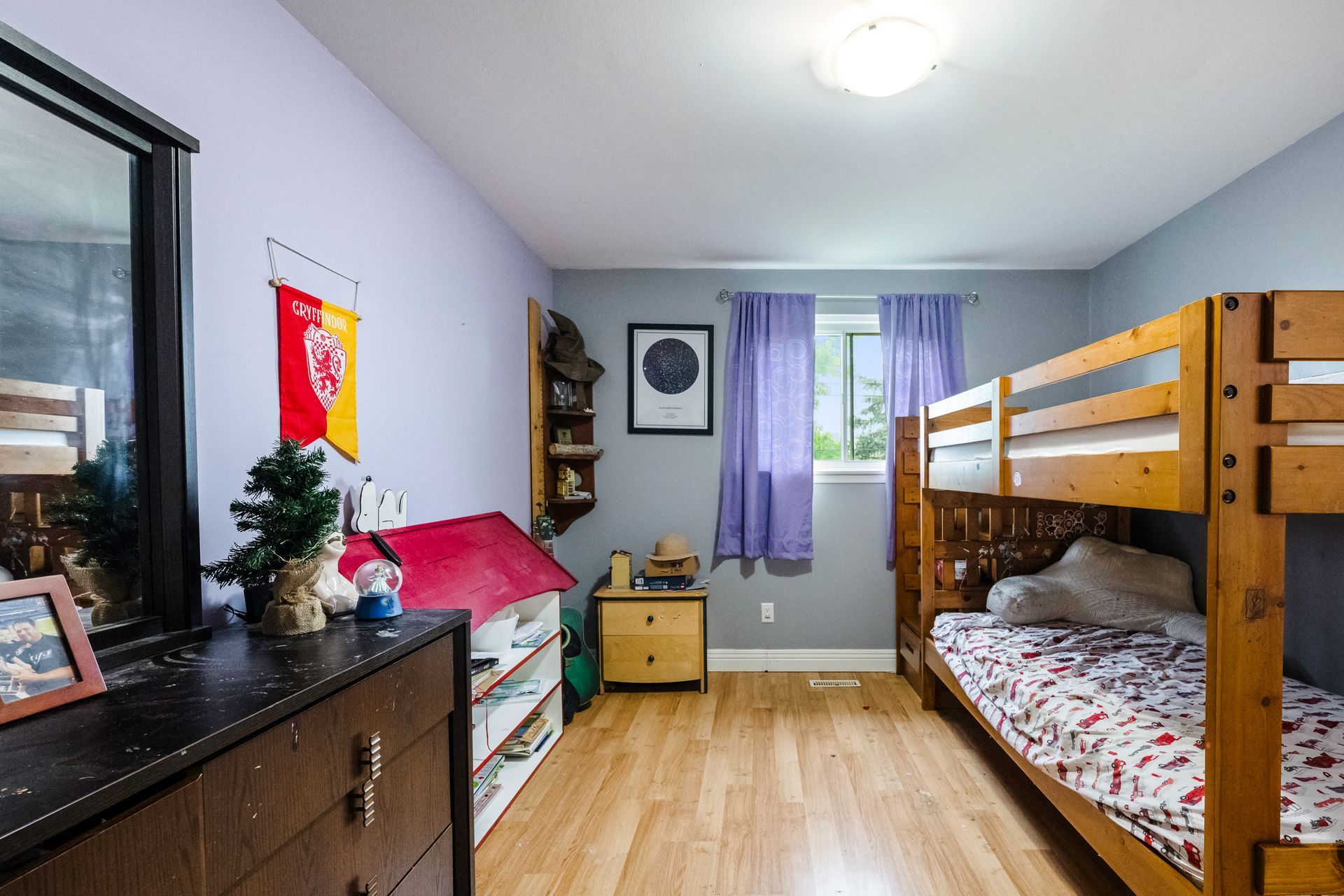 A bedroom with two bunk beds , a dresser , and a mirror.