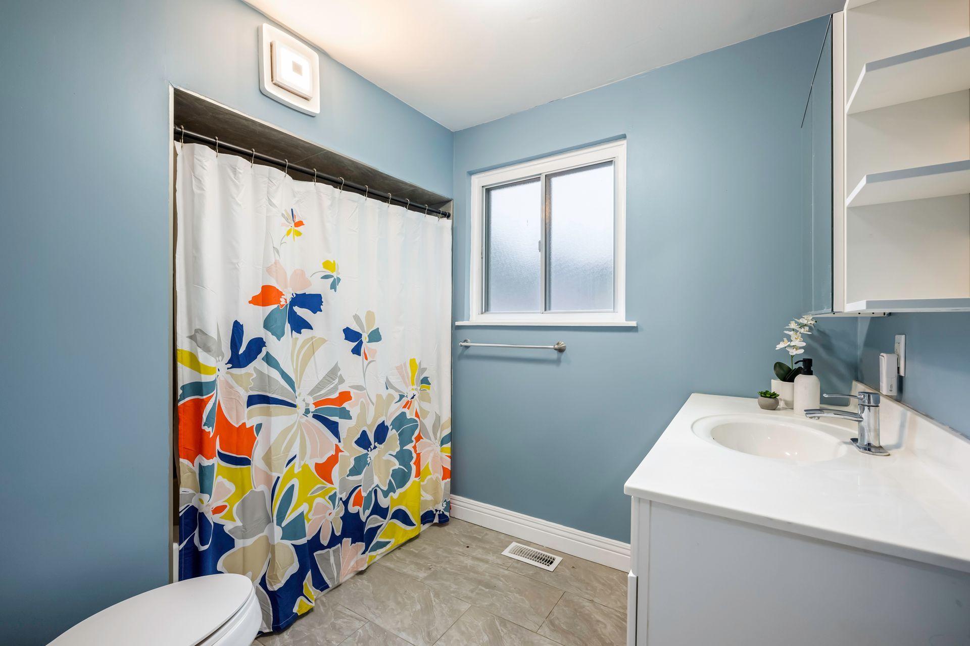 A bathroom with a toilet , sink and shower curtain.