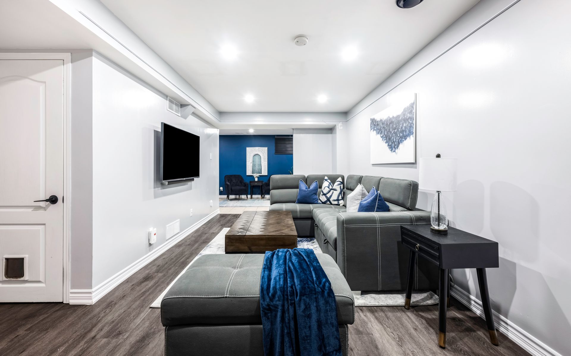 A living room with a couch , ottoman , table and television.