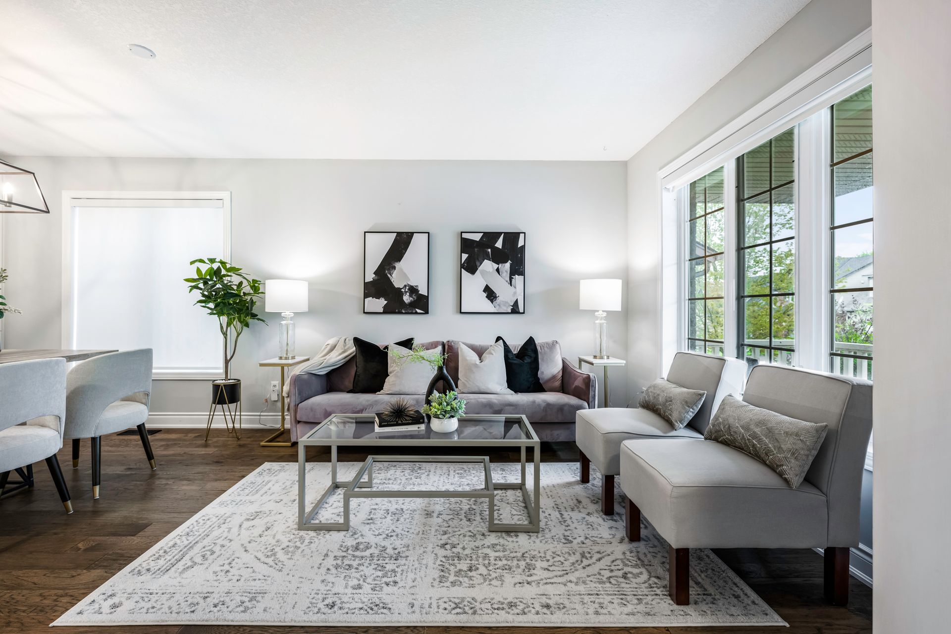 A living room with a couch , chairs , a coffee table and a rug.