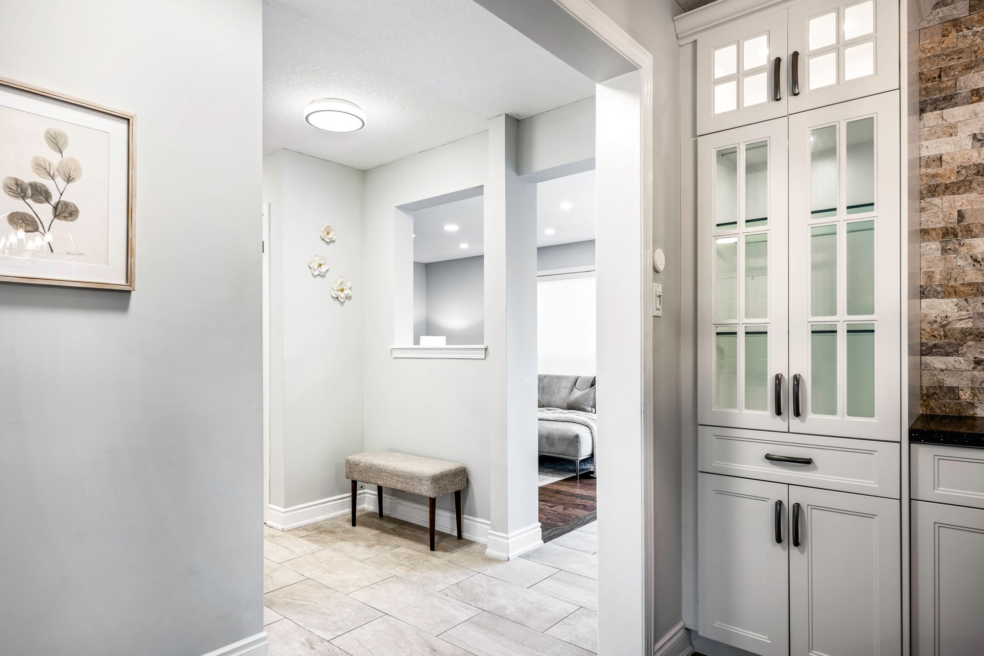 A hallway in a house with white cabinets and a bench.