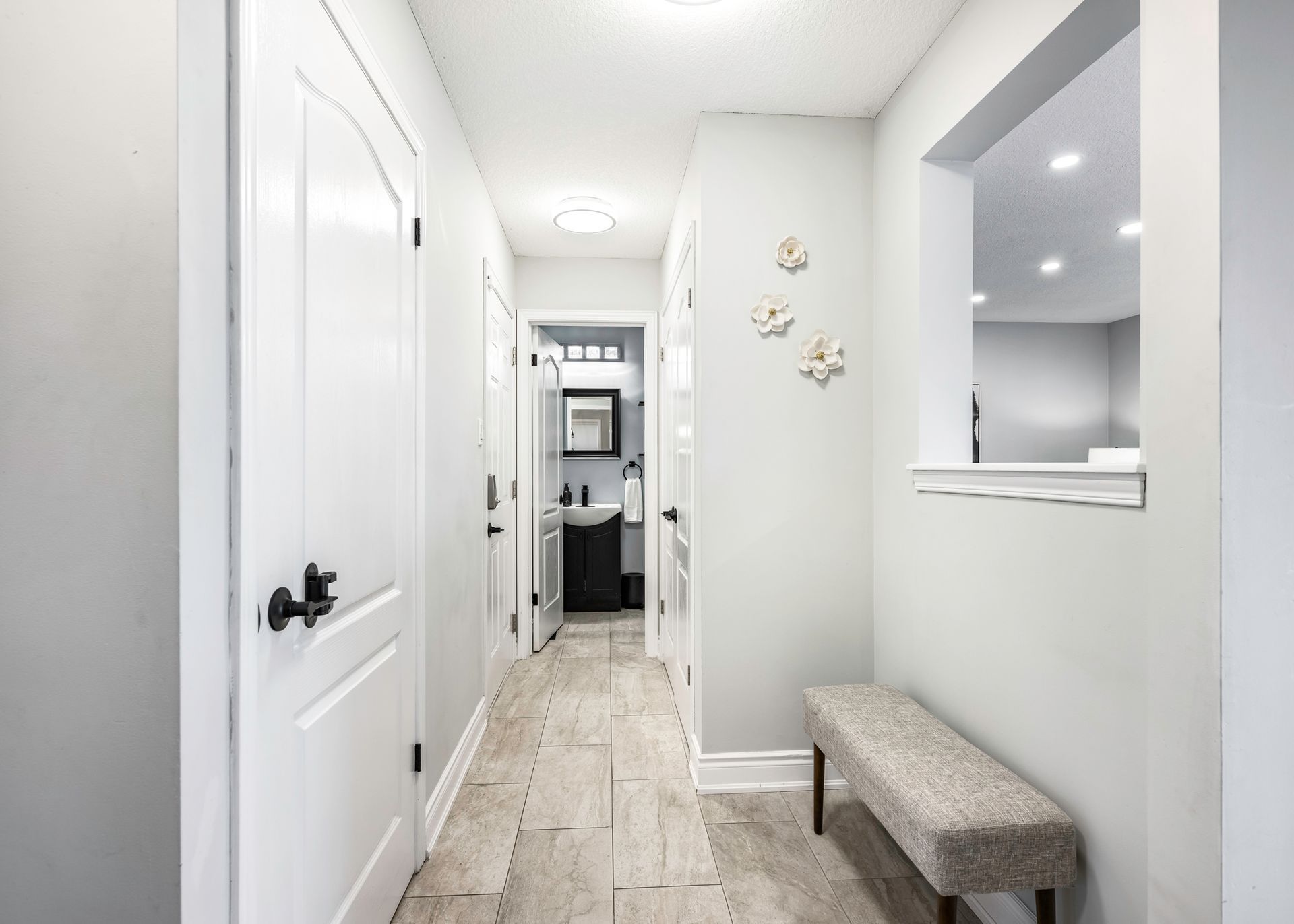 A long hallway with a bench and a mirror in a house.