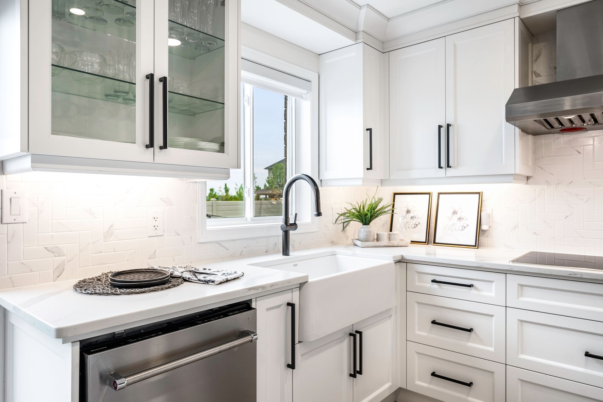A kitchen with white cabinets , stainless steel appliances , a sink , and a window.