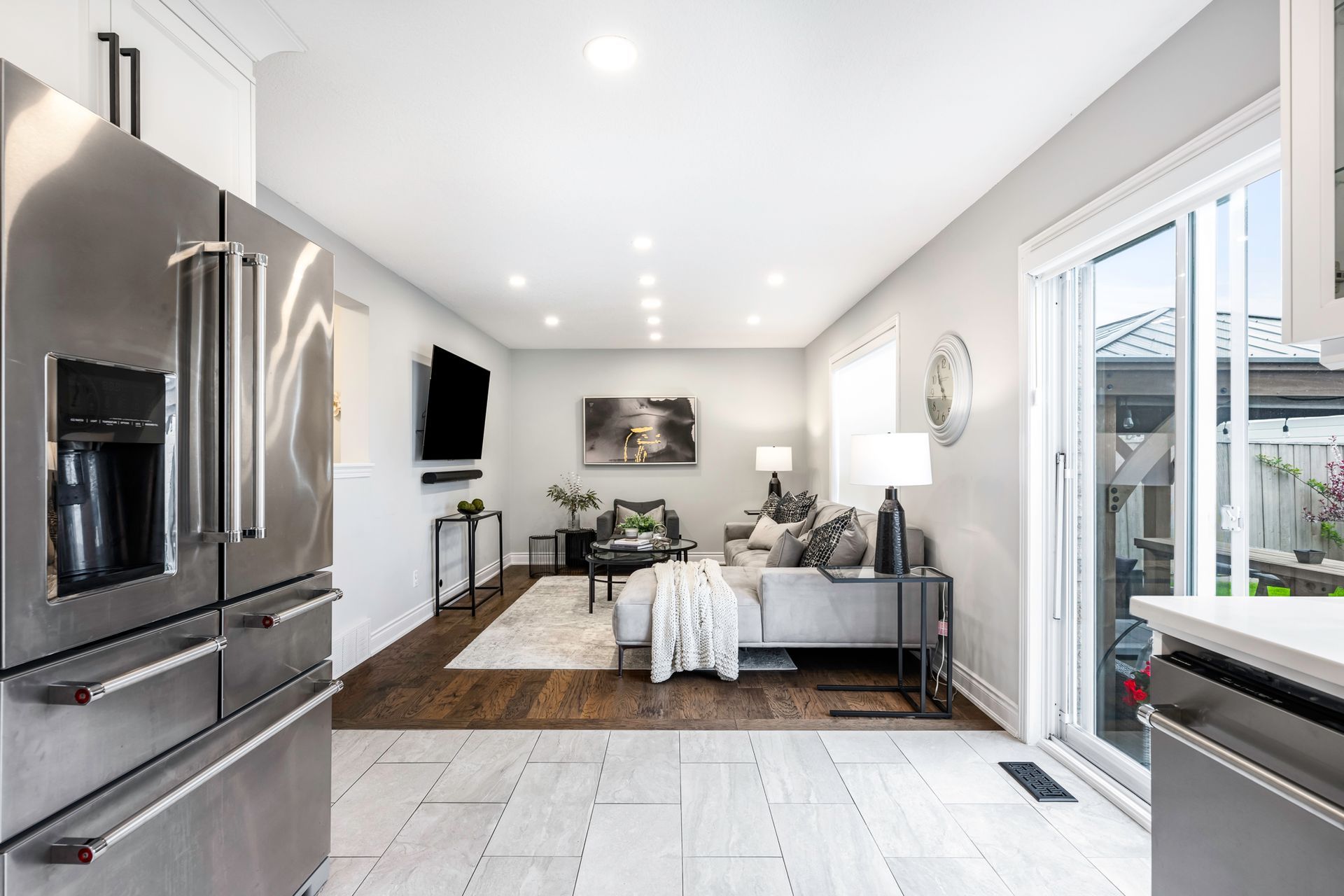 A living room with a sliding glass door and a stainless steel refrigerator.