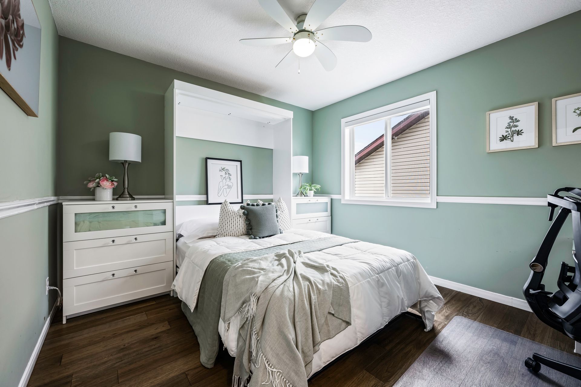 A bedroom with a bed , dresser , lamp and ceiling fan.