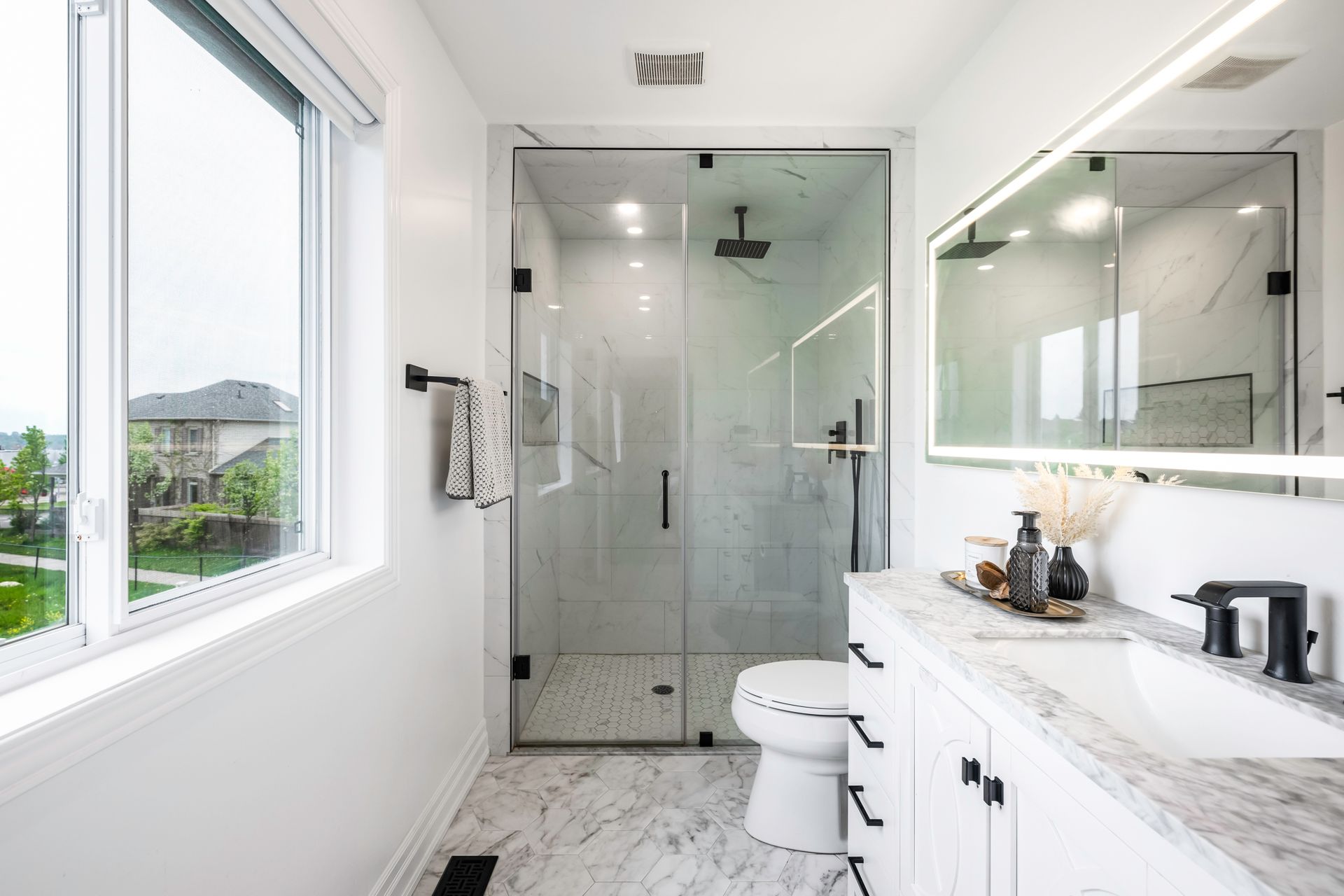 A bathroom with a toilet , sink , shower and mirror.