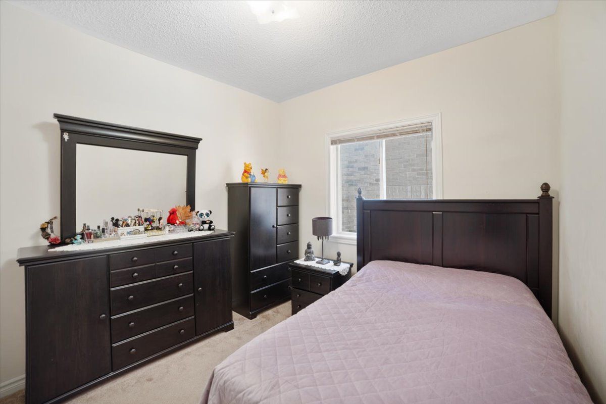 A bedroom with a bed , dresser , mirror and nightstand.