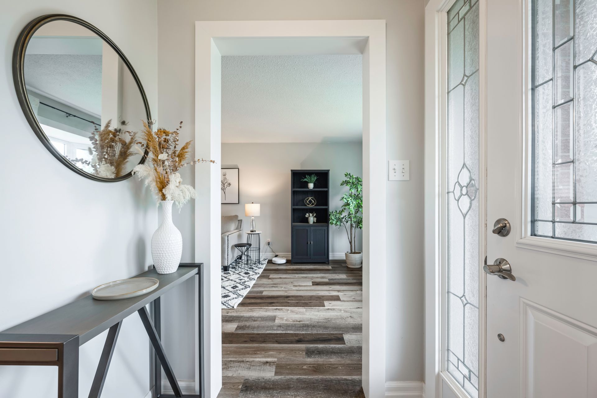 A hallway in a house with a mirror on the wall and a table.